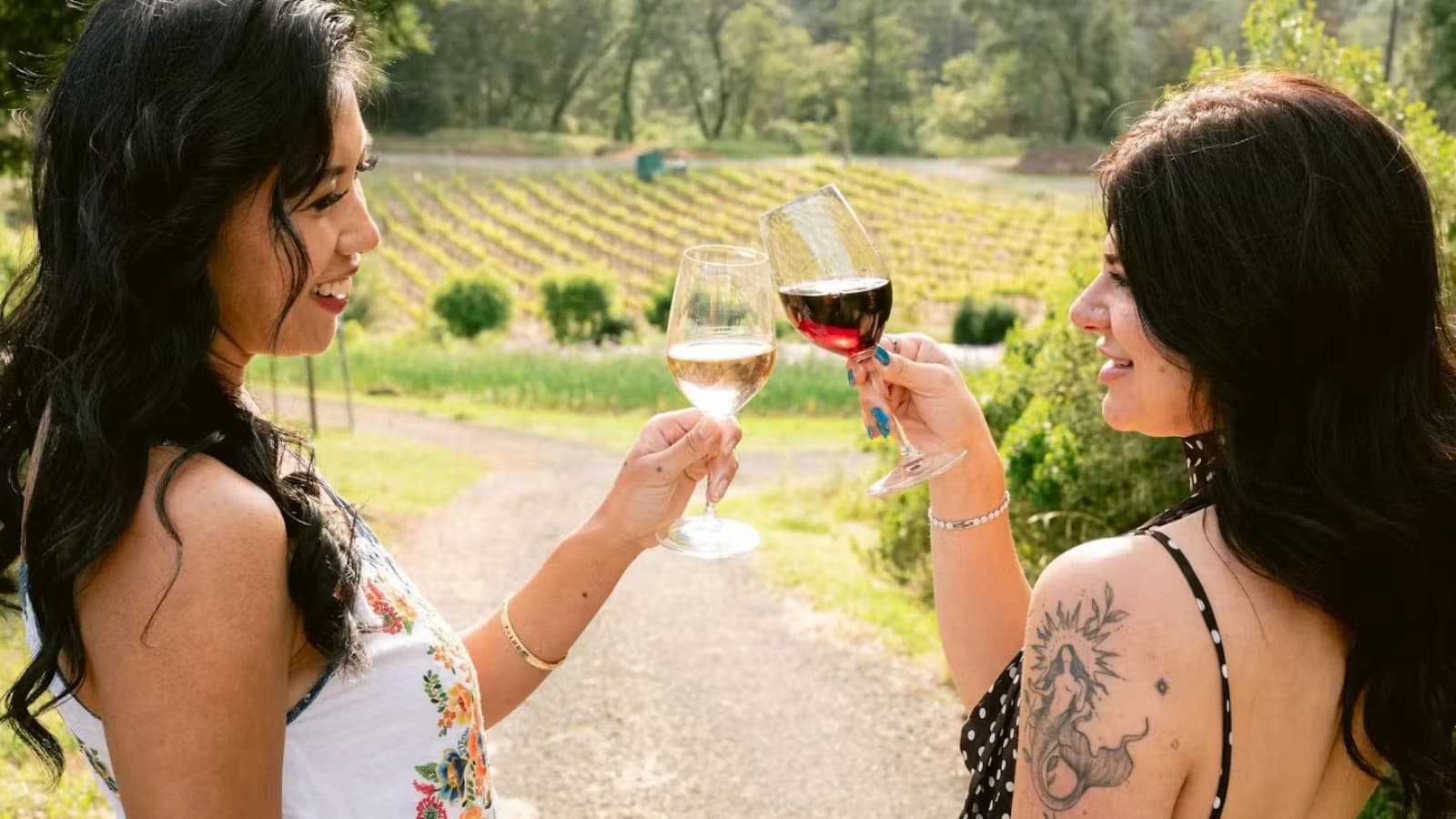 Two women toast with wine glasses at a vineyard