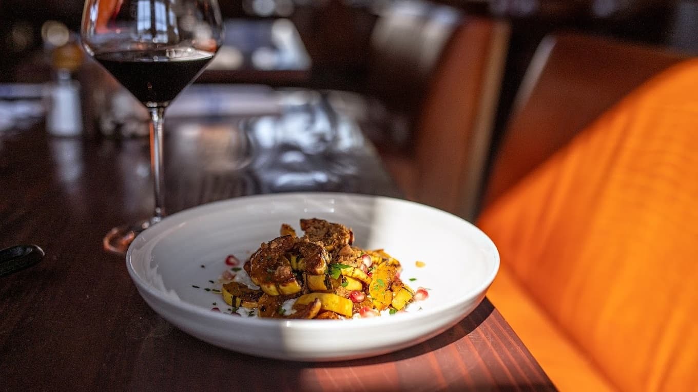 Gourmet squash dish with red wine glass nearby.