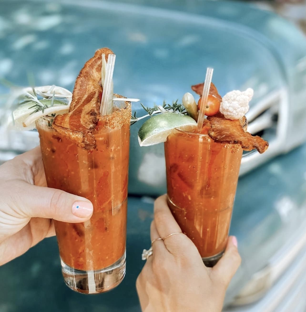 Two Bloody Mary cocktails with bacon and lime.