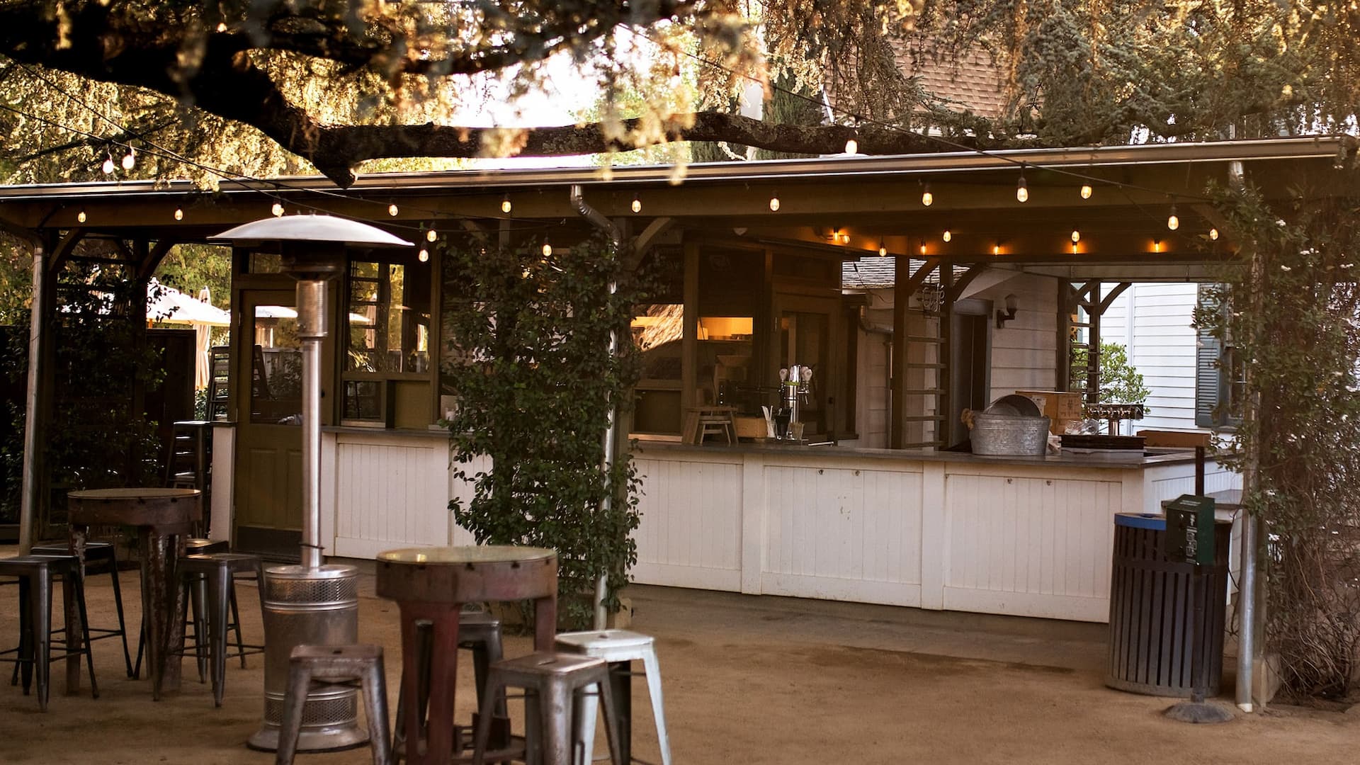 Outdoor bar with stools and string lights.