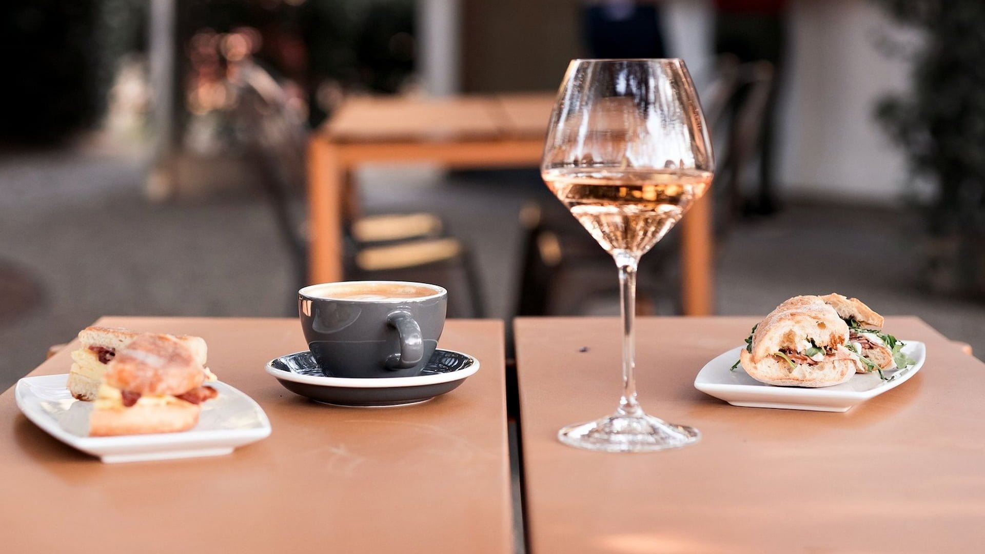 Coffee, wine, and sandwiches on a café table.
