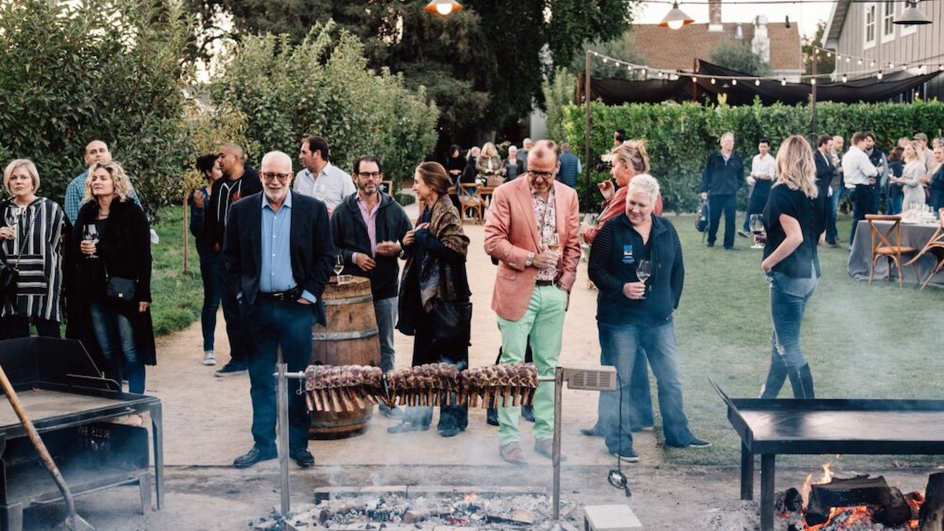Outdoor gathering with people and barbecue grill.