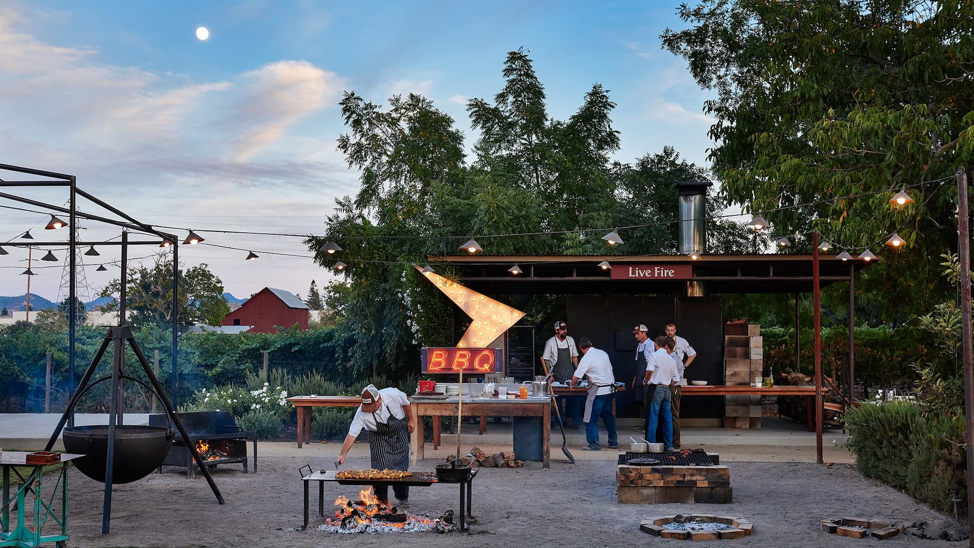 Outdoor barbecue with chefs grilling and BBQ sign.