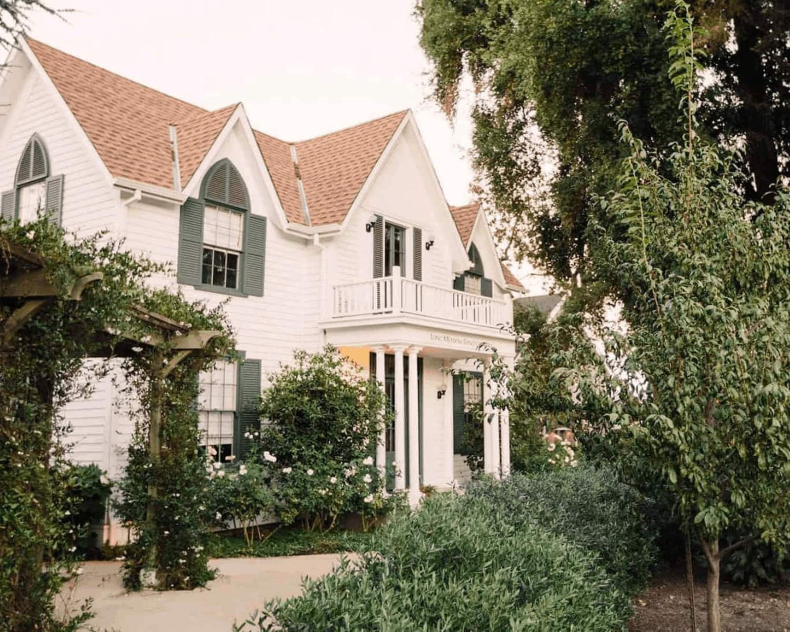 Charming white farmhouse surrounded by greenery.