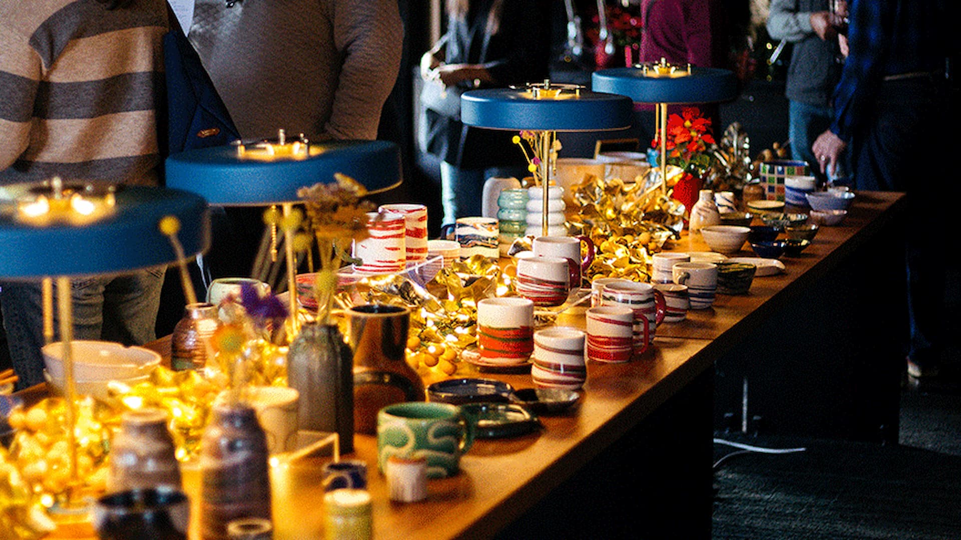 Table with pottery, lamps, and decor displayed at event.