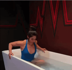 Woman in blue swimsuit stepping into bathtub
