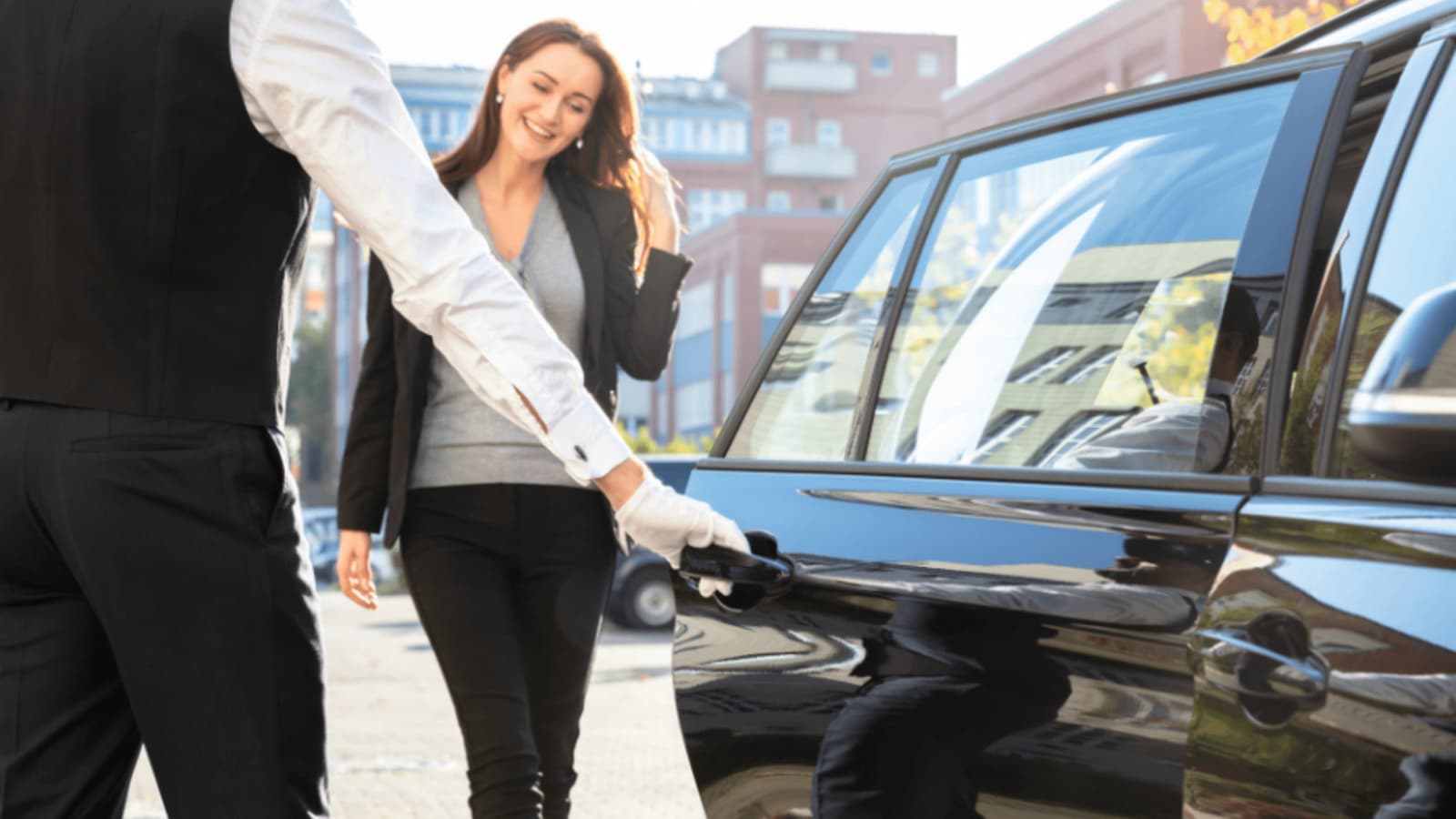 Chauffeur opening door for happy woman