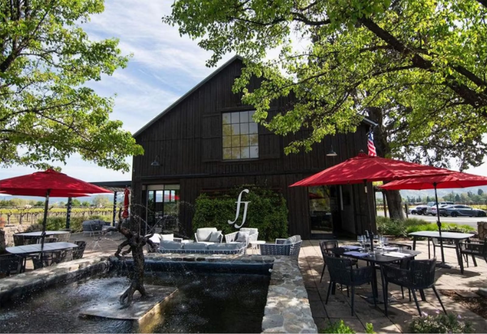 Outdoor seating area with red umbrellas and fountain.