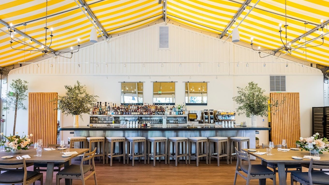 Modern restaurant interior with bar and yellow canopy.