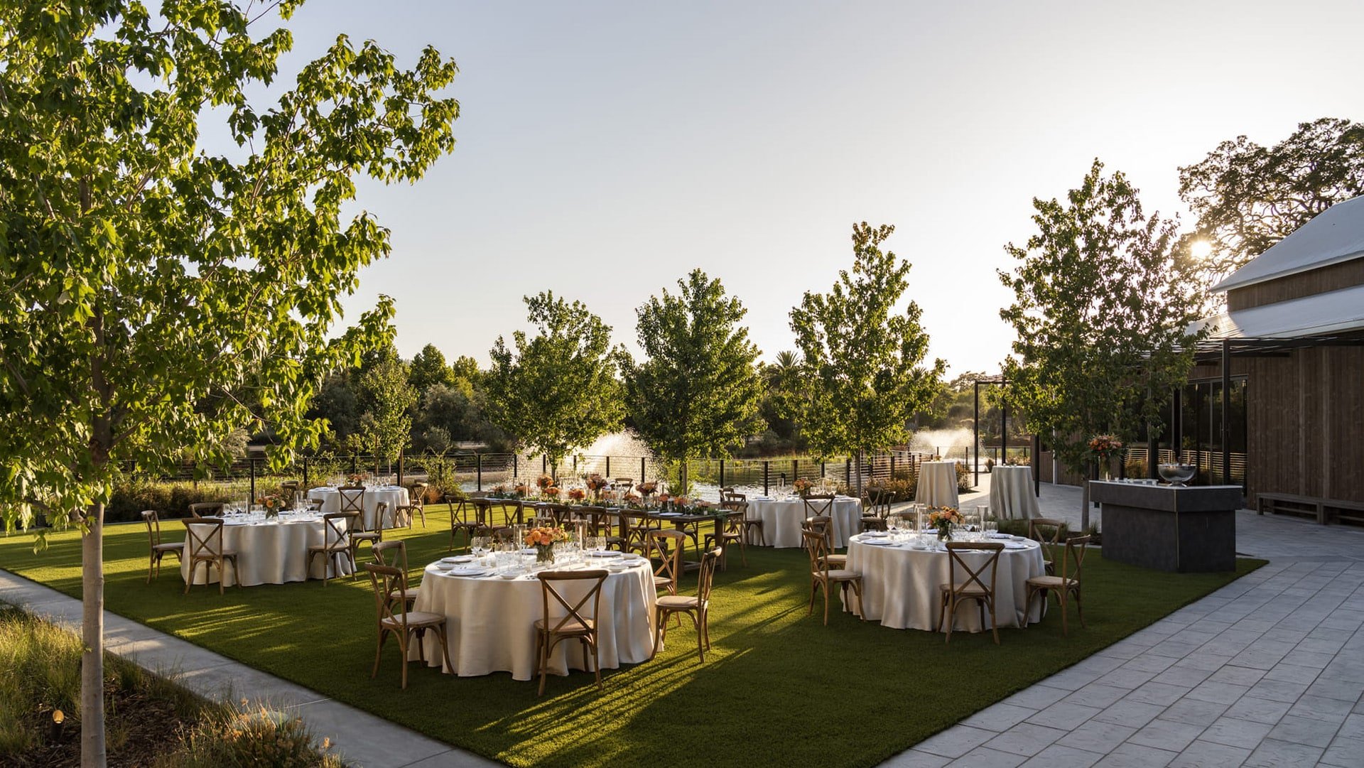 Outdoor wedding reception setup with round tables and chairs.