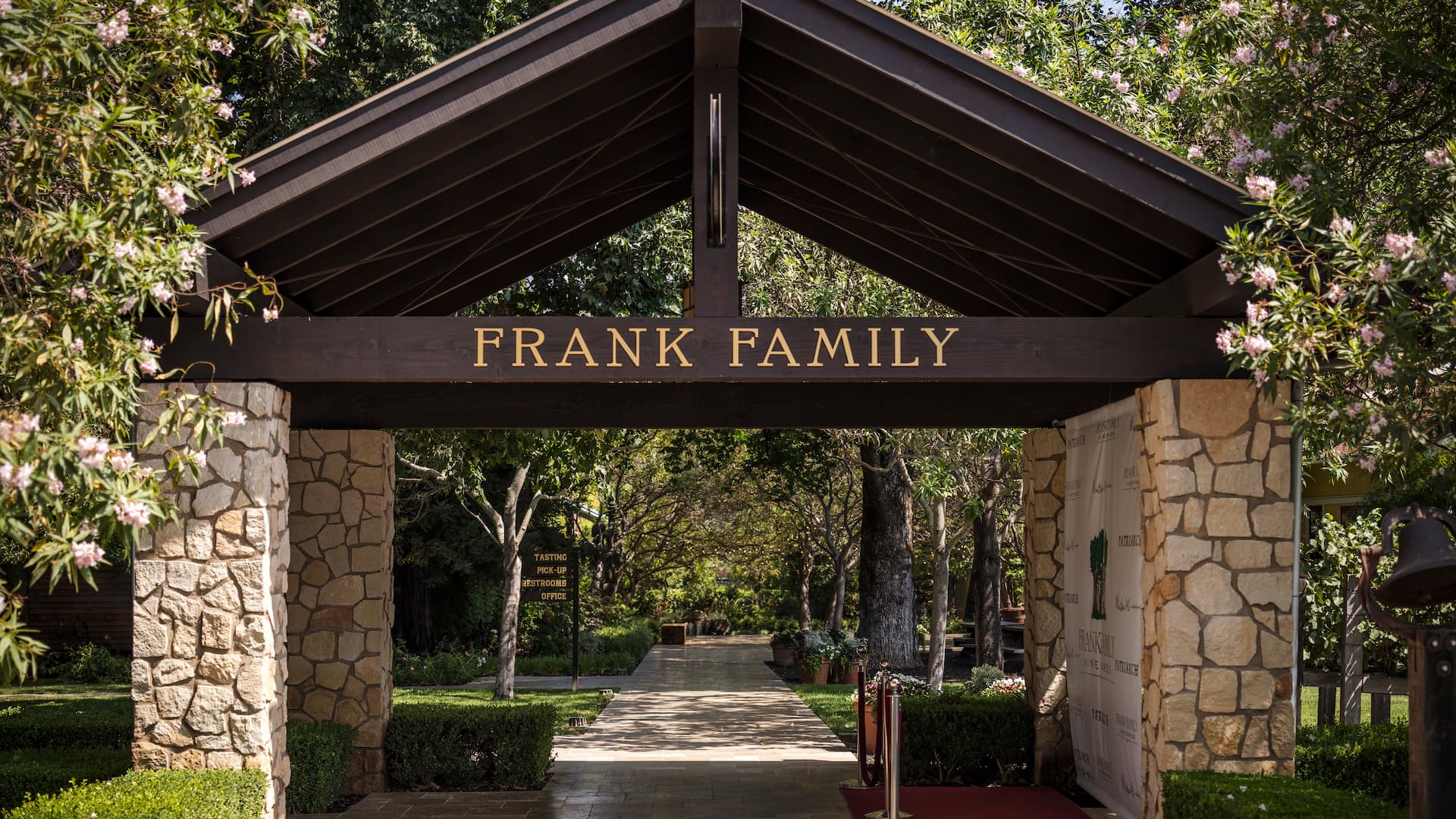 Frank Family winery entrance, stone columns, lush greenery.