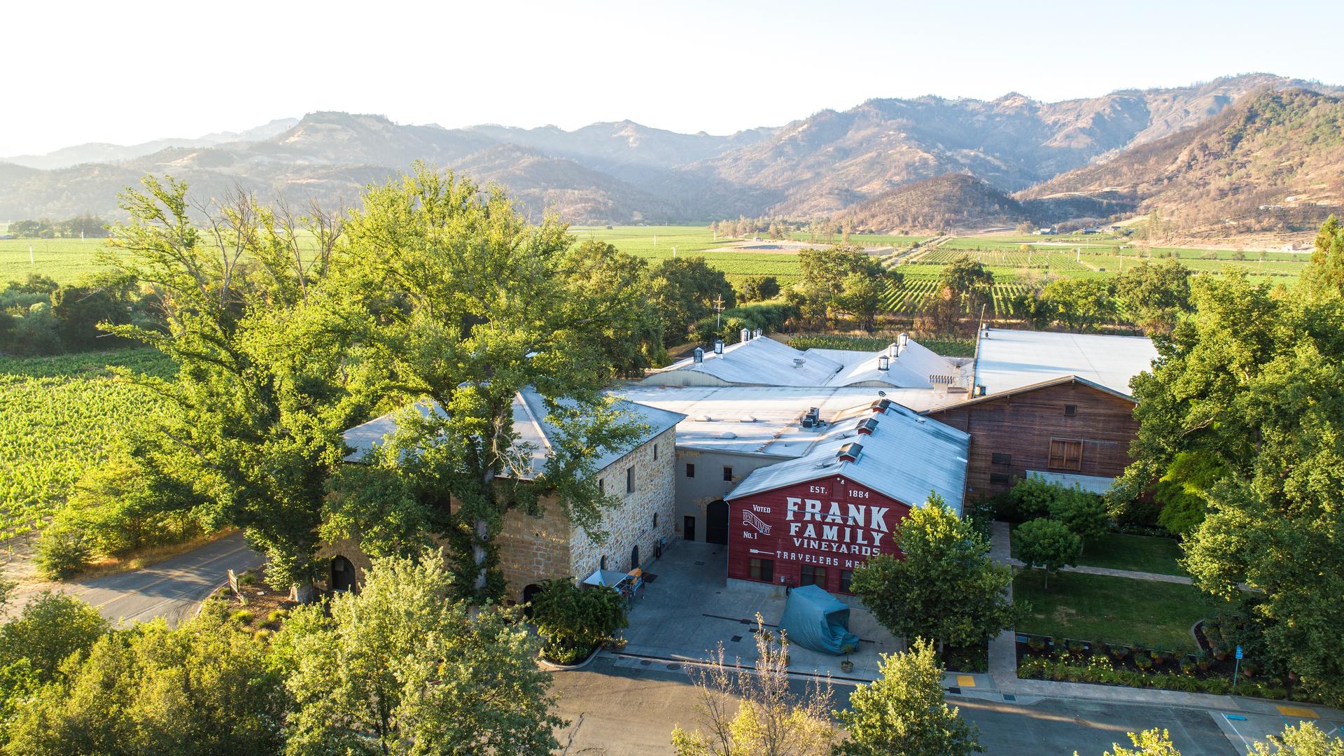Aerial view of vineyard with buildings and mountains.