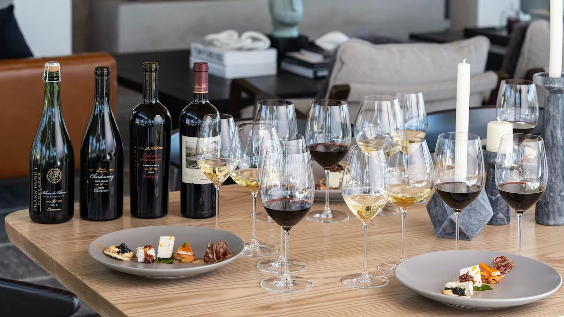 Wine bottles and glasses with appetizers on table.