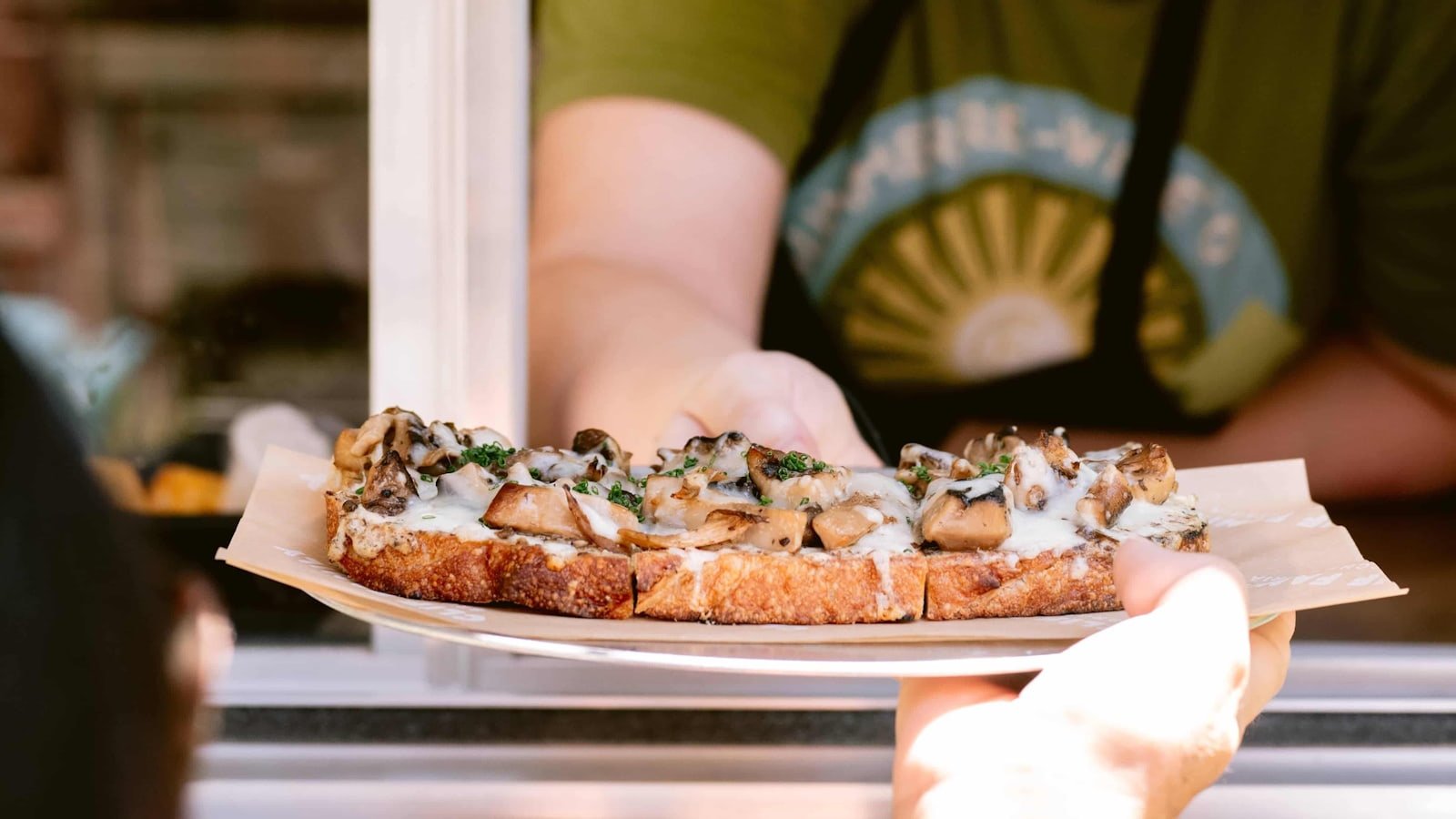 Person serving mushroom toast through window