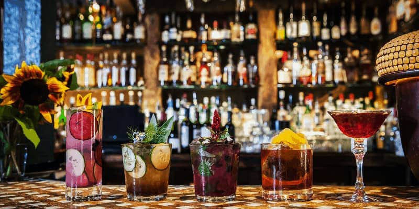 Five cocktails on bar with sunflower.