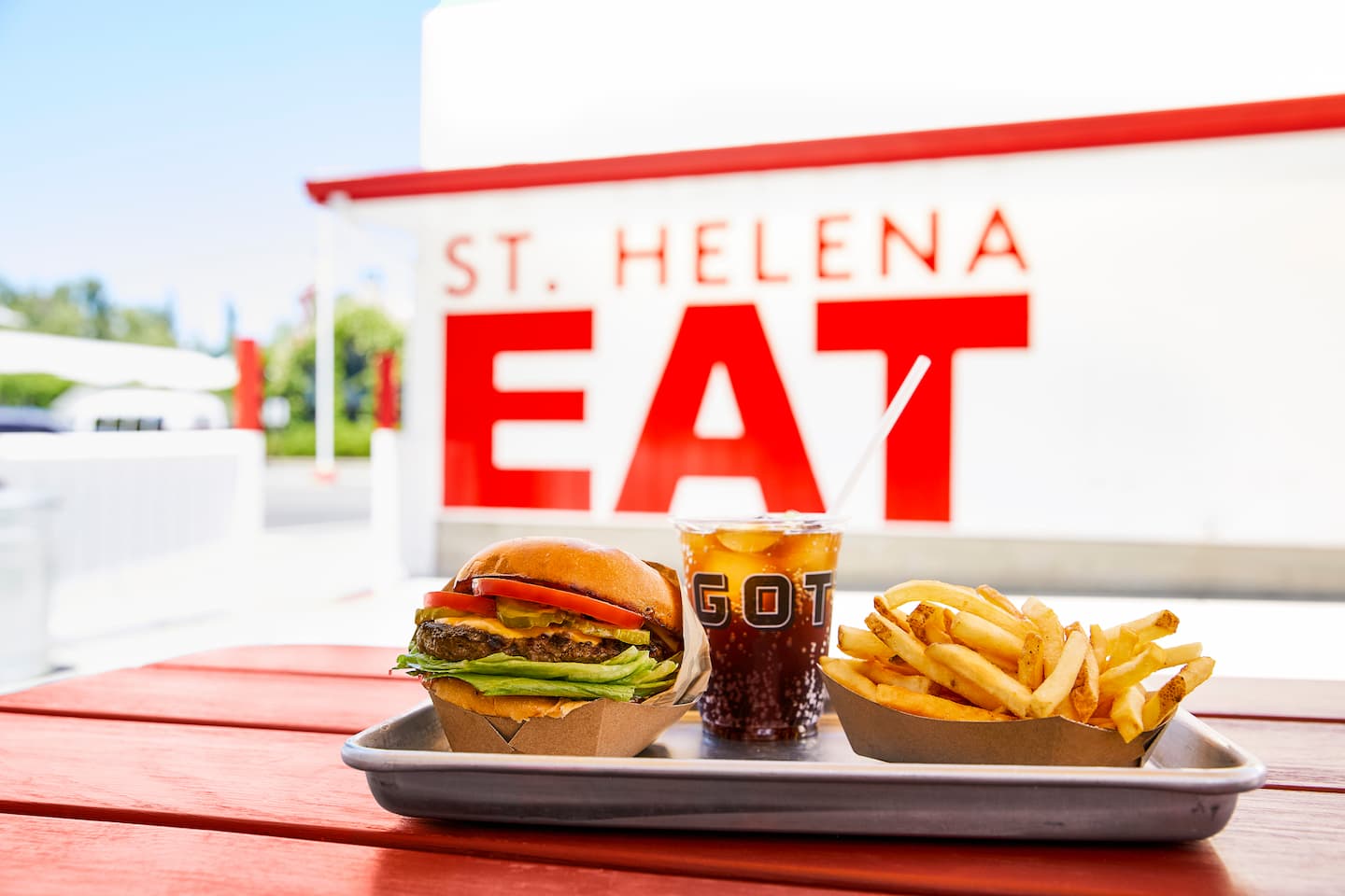 Burger, fries, and soda on outdoor table