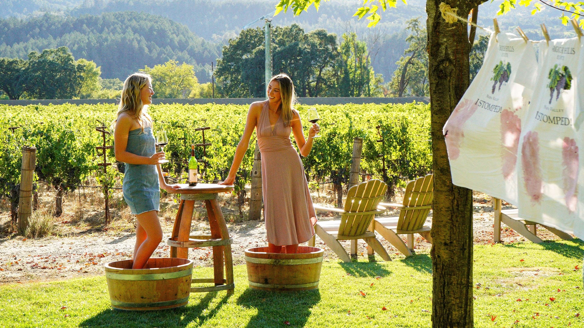 Two women wine tasting while stomping grapes in vineyard