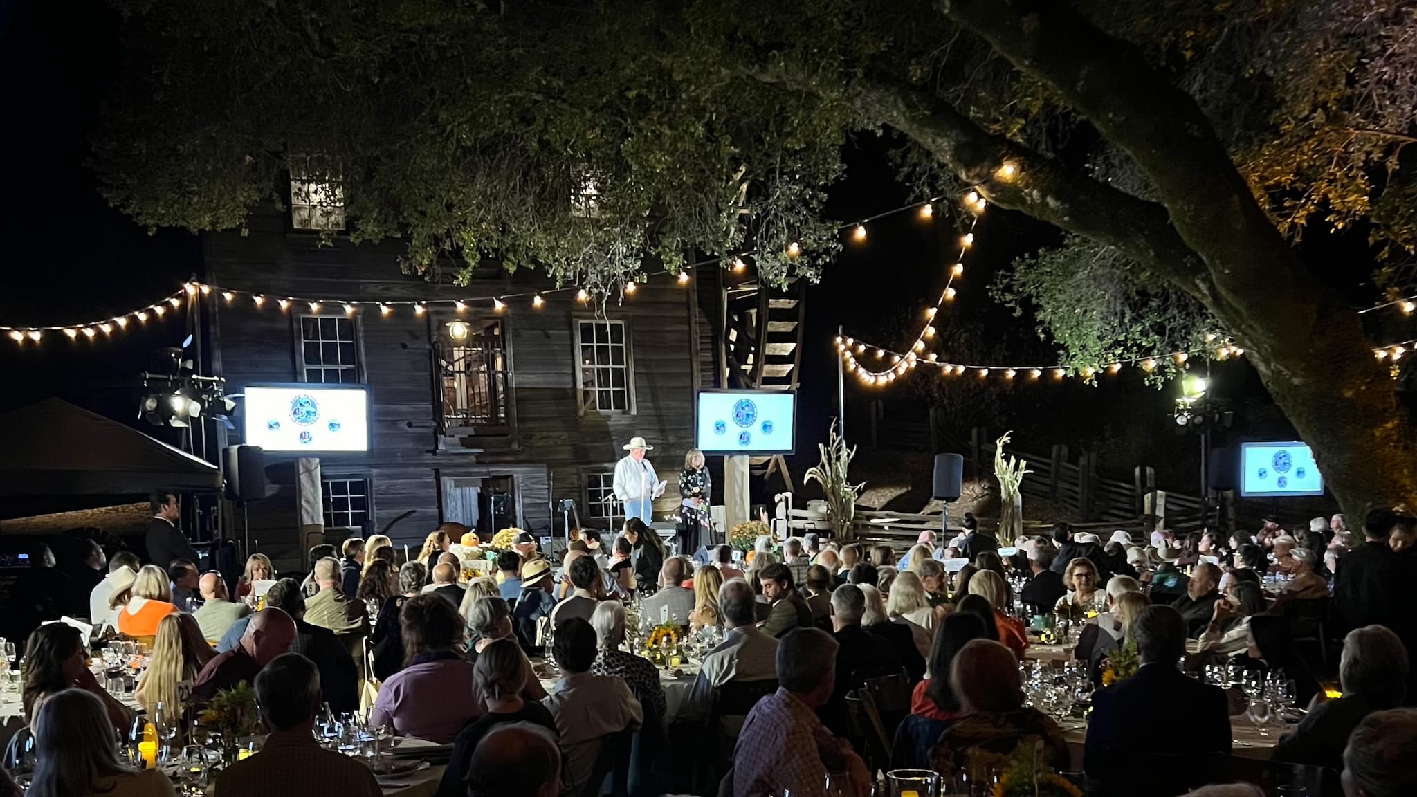 Outdoor evening event with string lights and crowd.