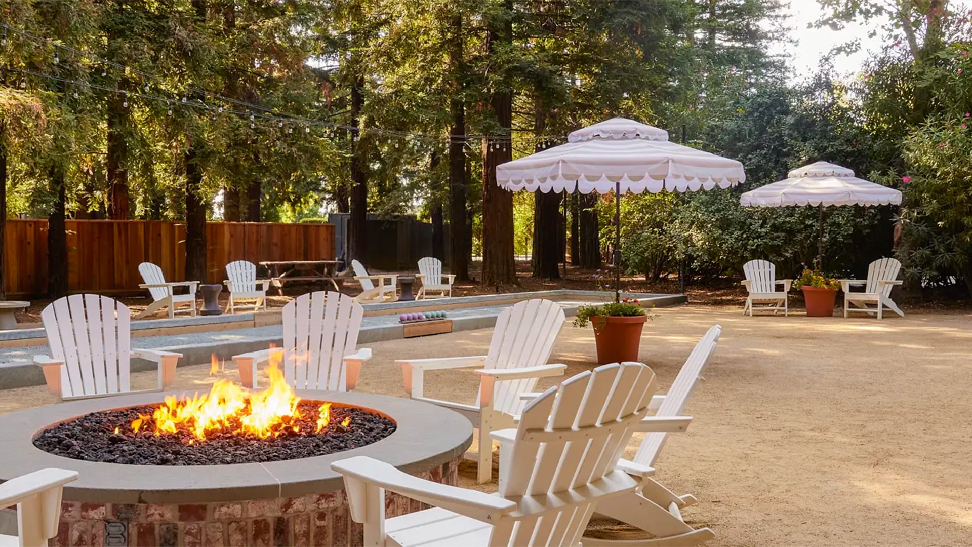 Fire pit patio with white Adirondack chairs and umbrellas