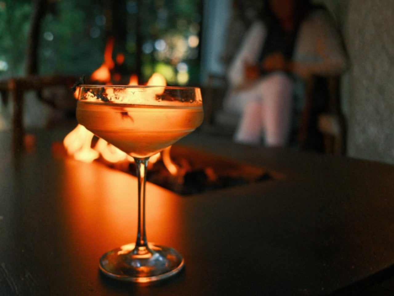 Cocktail in coupe glass by outdoor fire pit