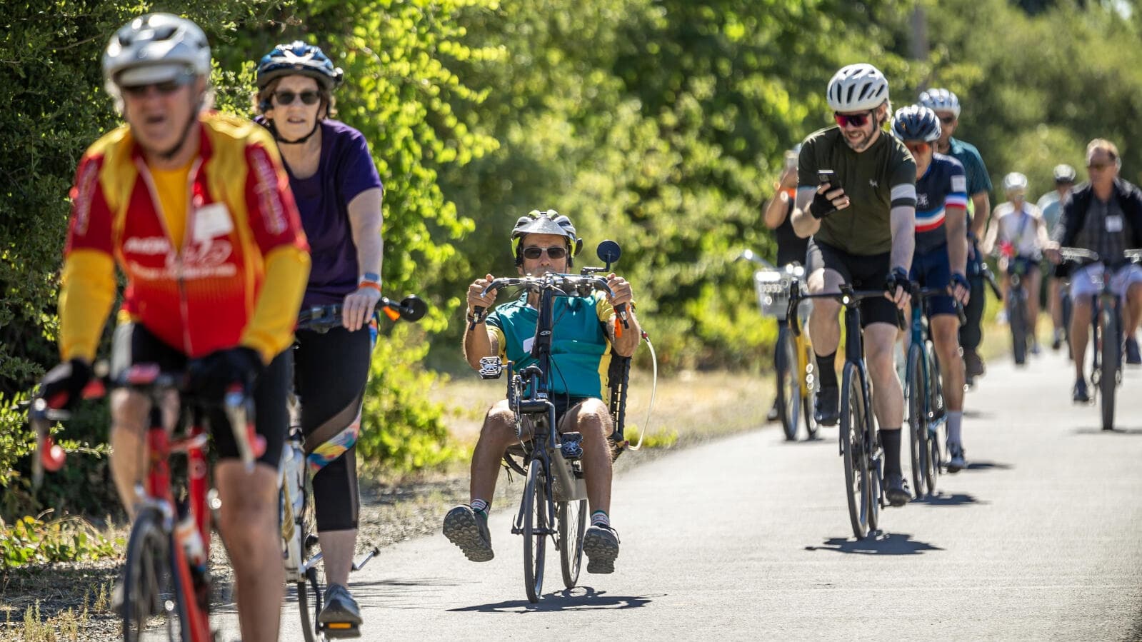 Group of cyclists riding on a sunny path.