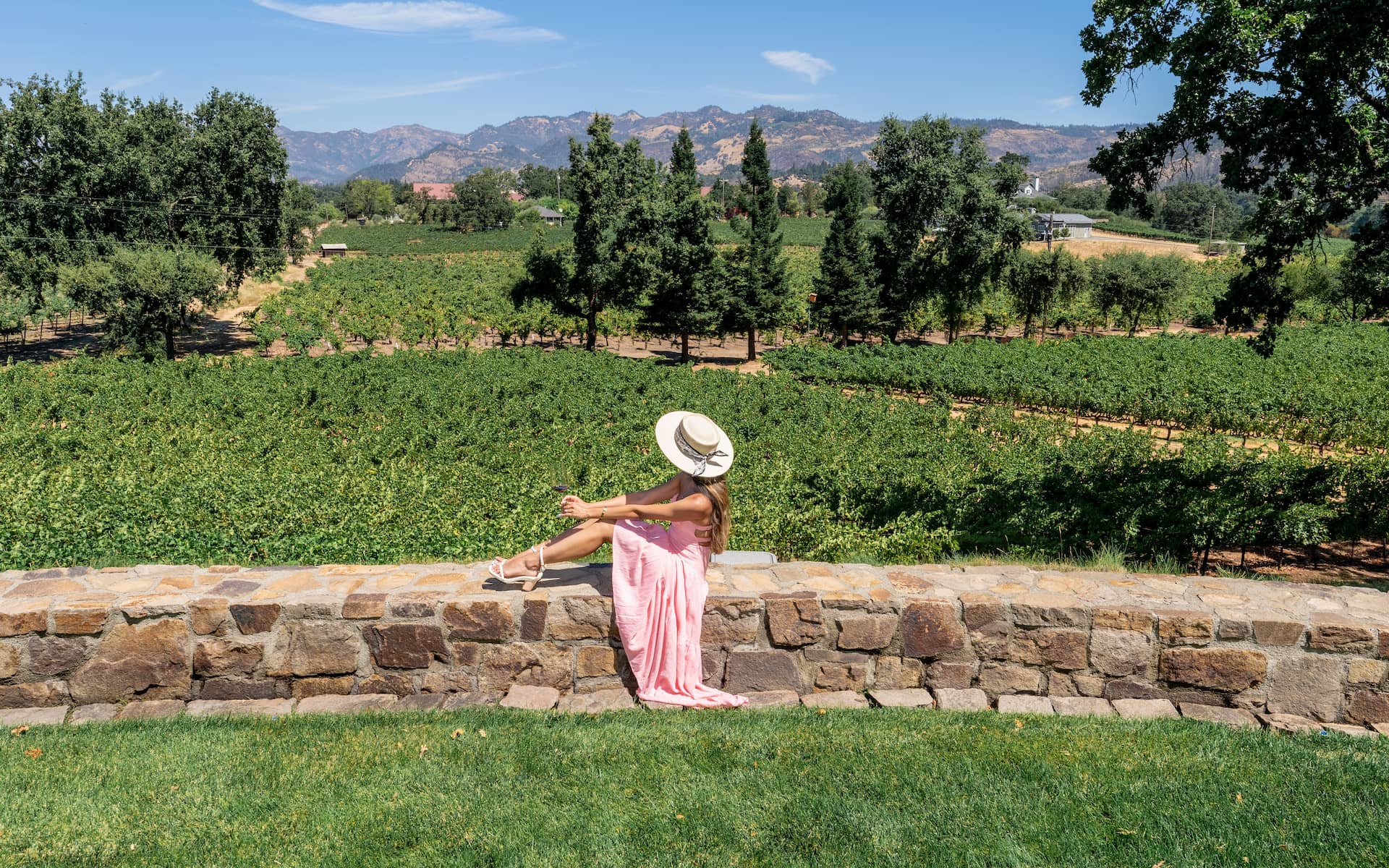 Woman in hat relaxing by vineyard view.
