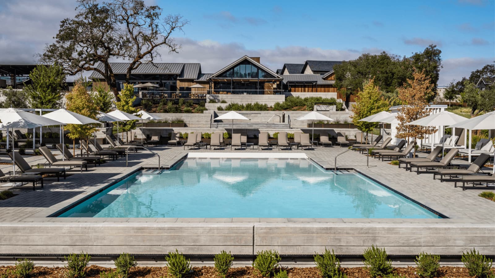 Luxury hotel pool with lounge chairs and umbrellas.