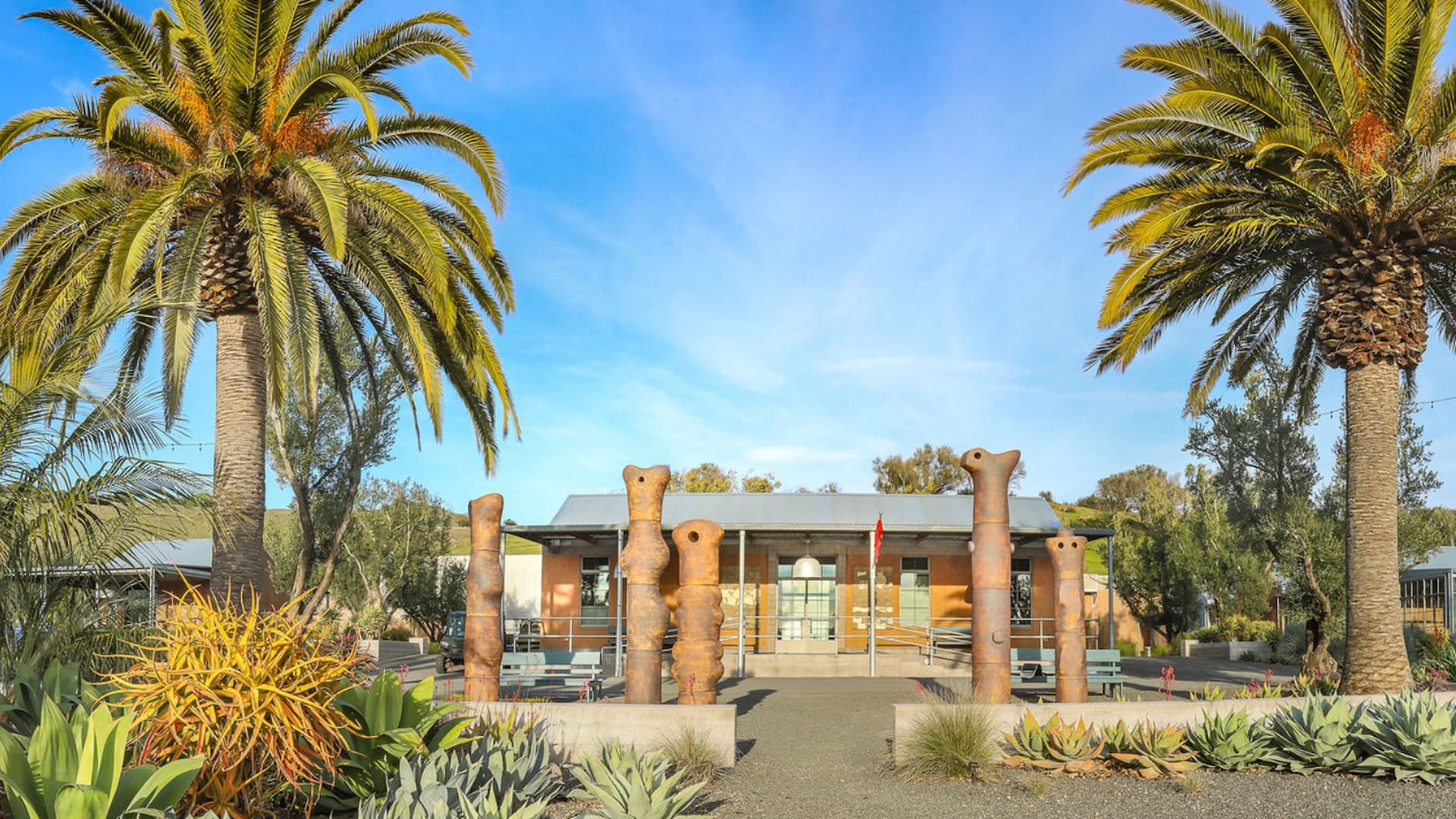Modern building with palm trees and sculptures