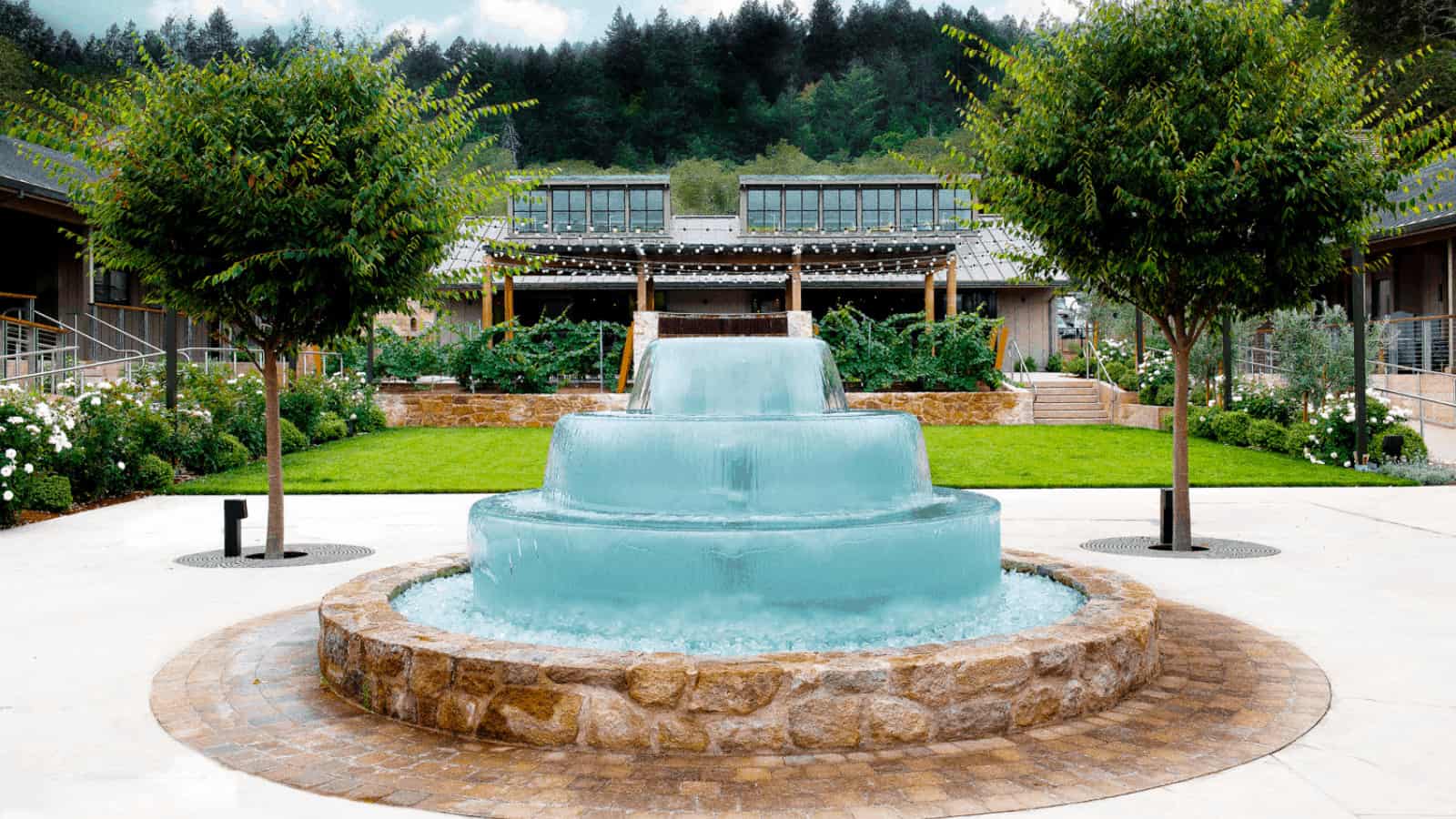 Tiered fountain in lush garden courtyard.