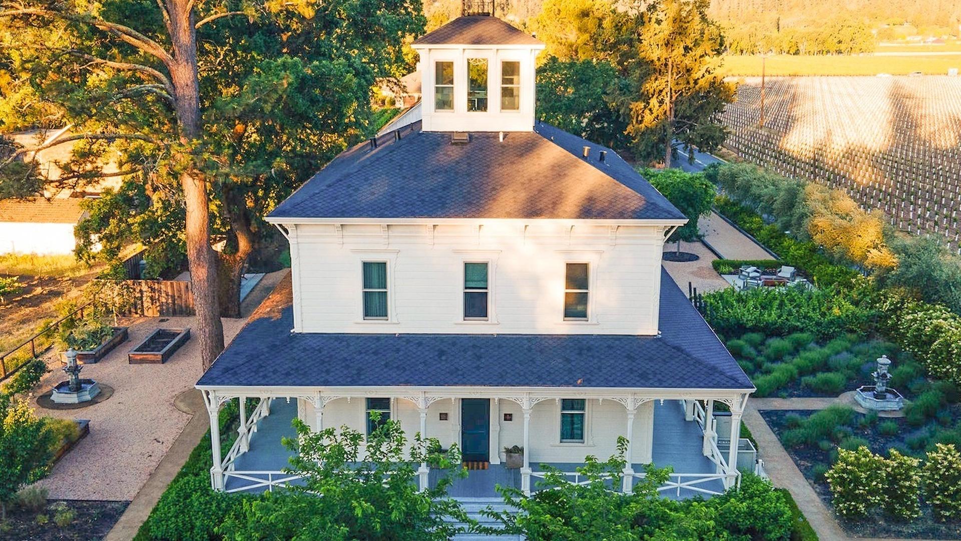 Aerial view of white farmhouse surrounded by vineyards.