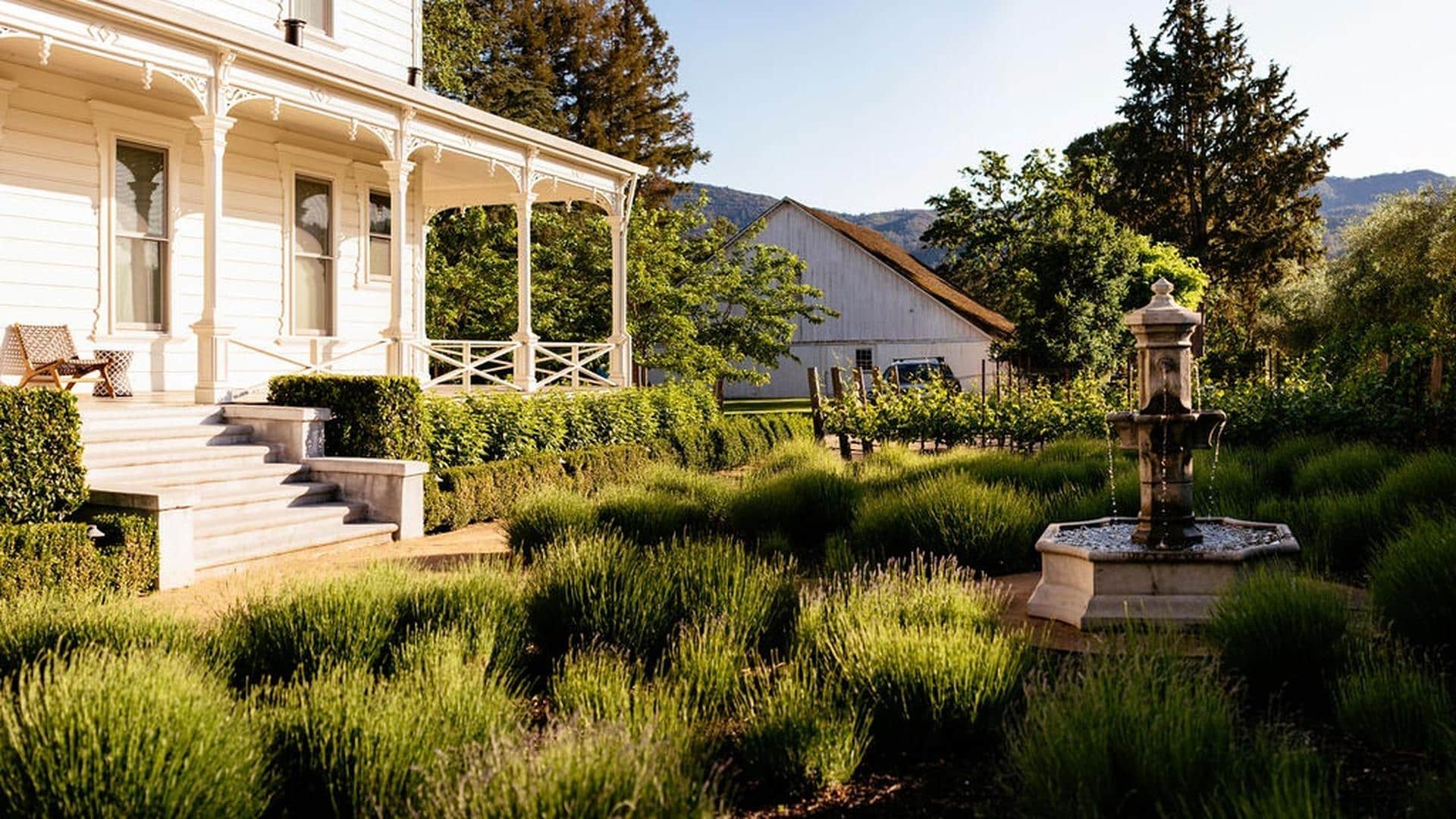 Charming farmhouse garden with fountain and veranda.