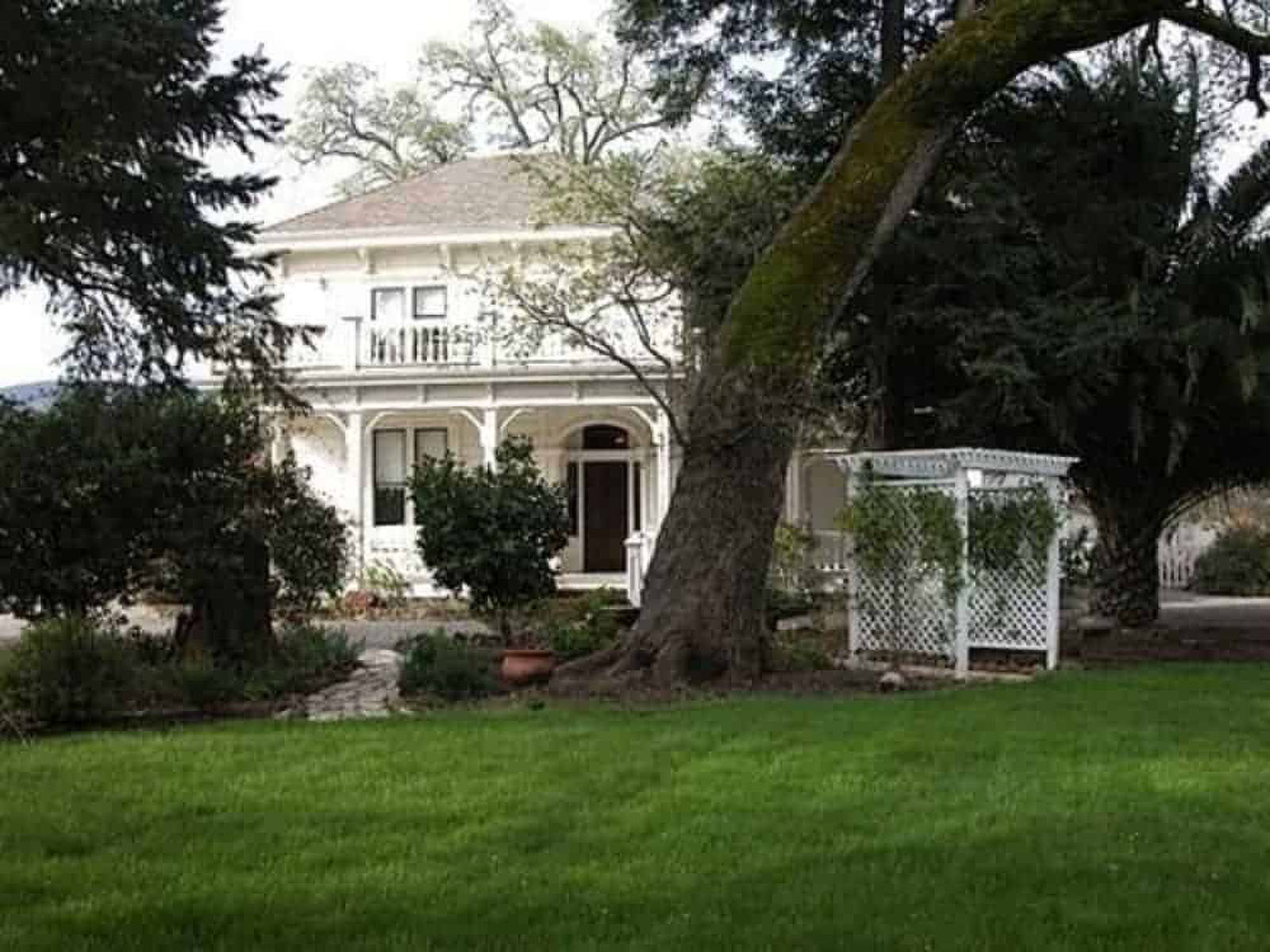Victorian house with lush green garden and gazebo.