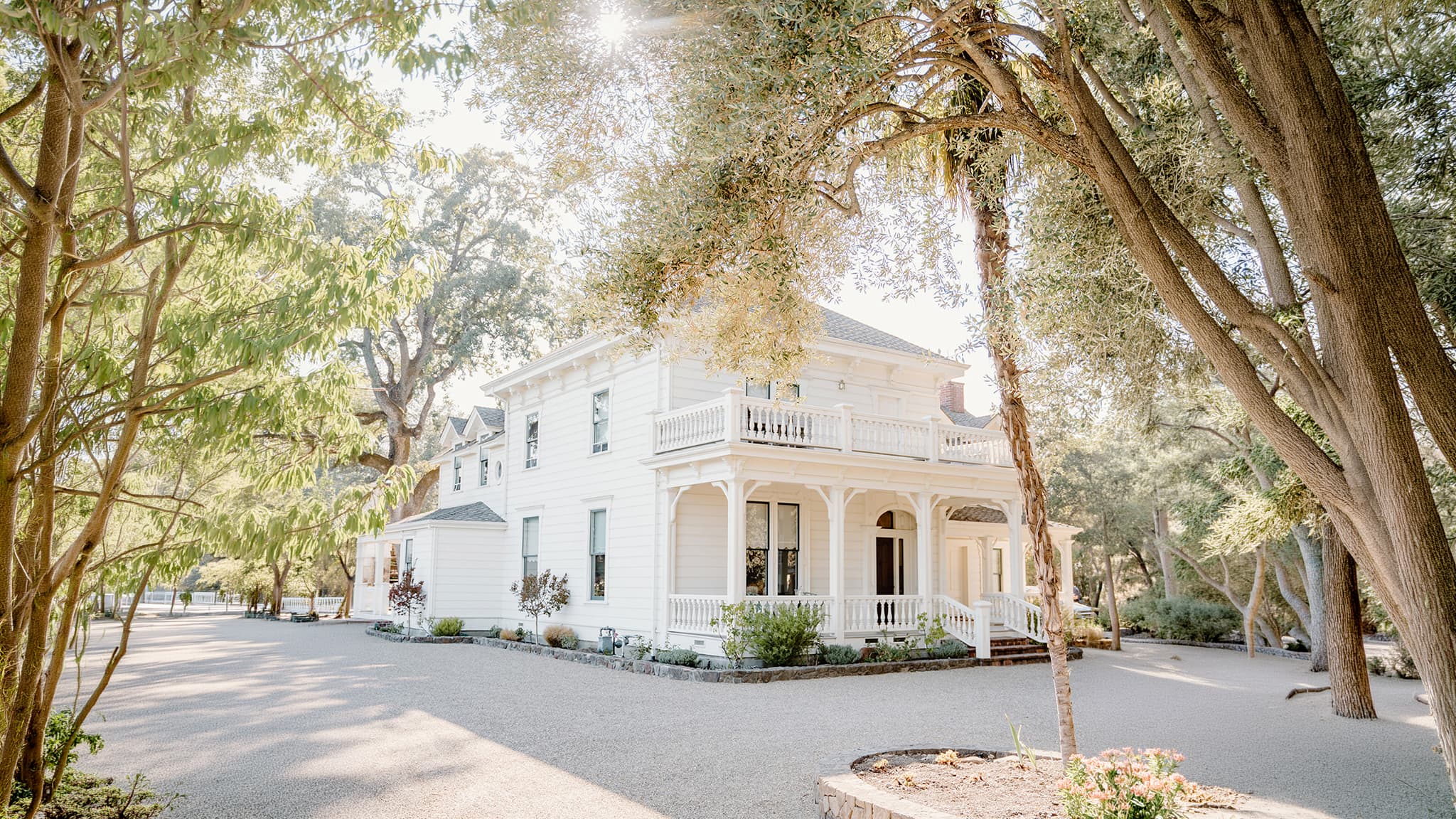 White Victorian house surrounded by tall trees