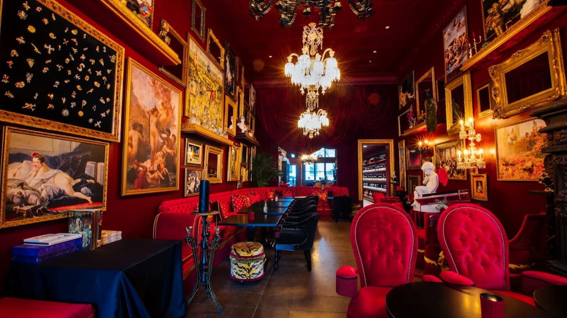 Luxurious red room with art and chandeliers.