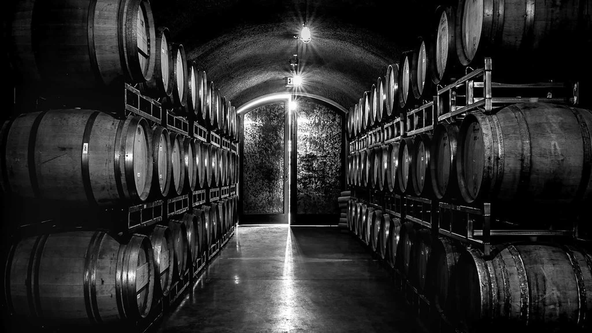 Dimly lit wine cellar with wooden barrels.