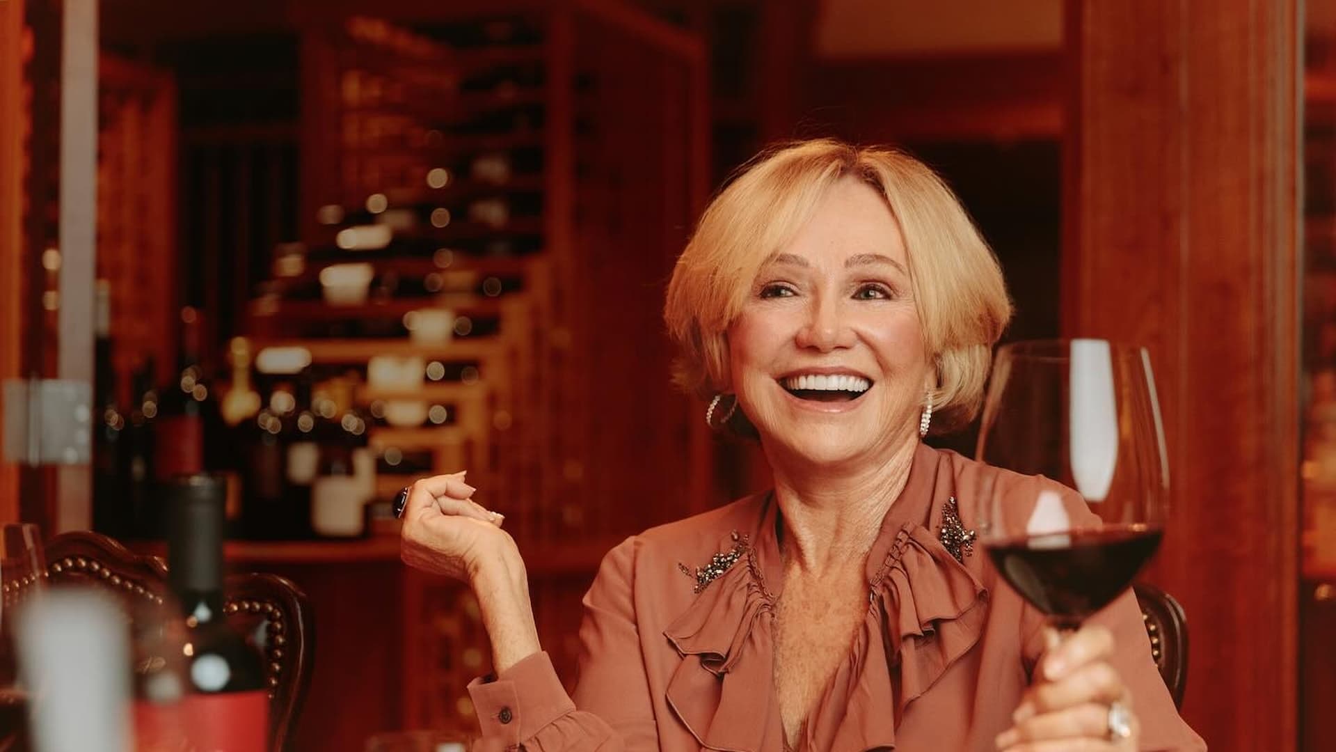 Smiling woman holding a glass of red wine.