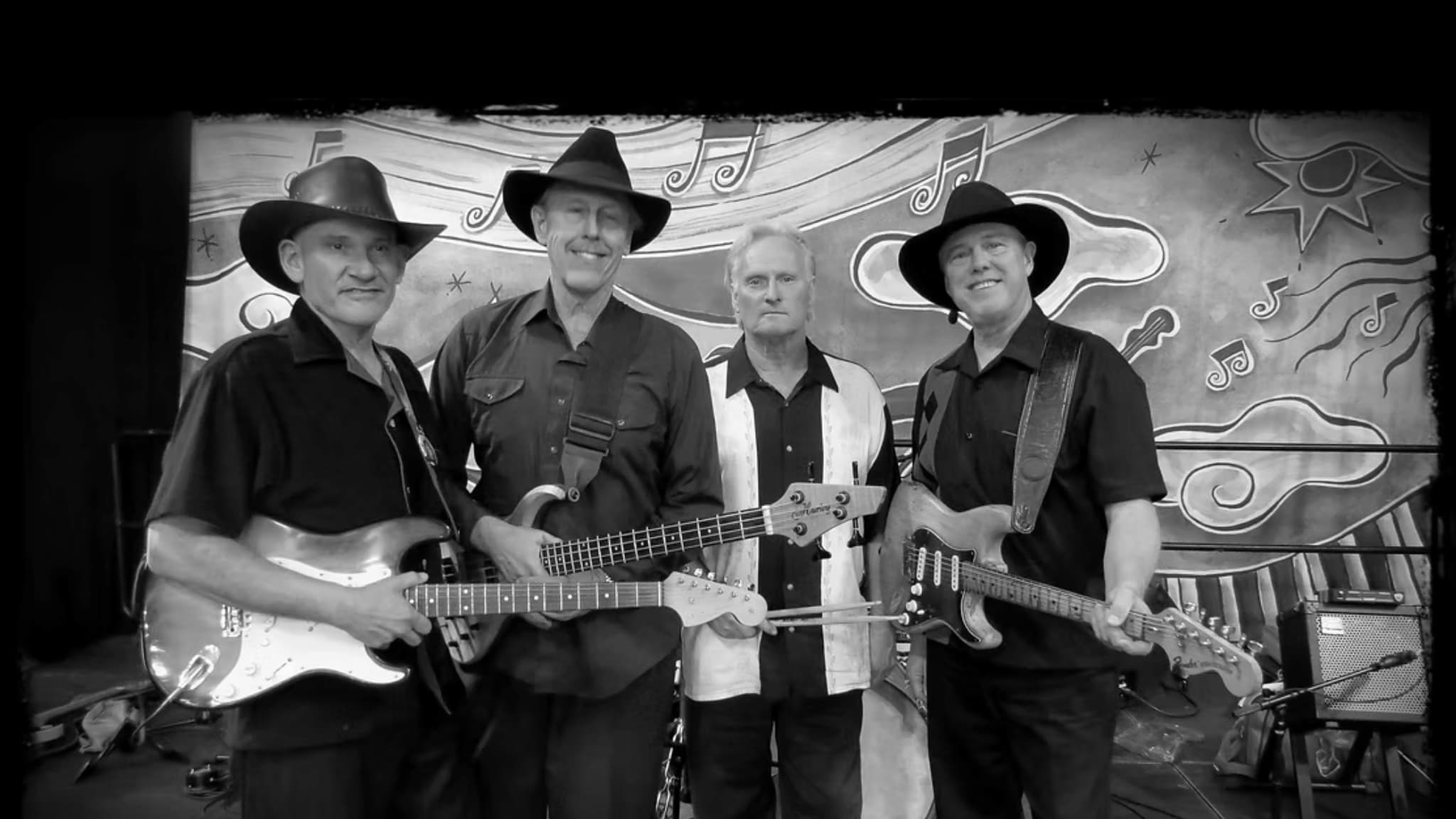 Four musicians in cowboy hats with guitars