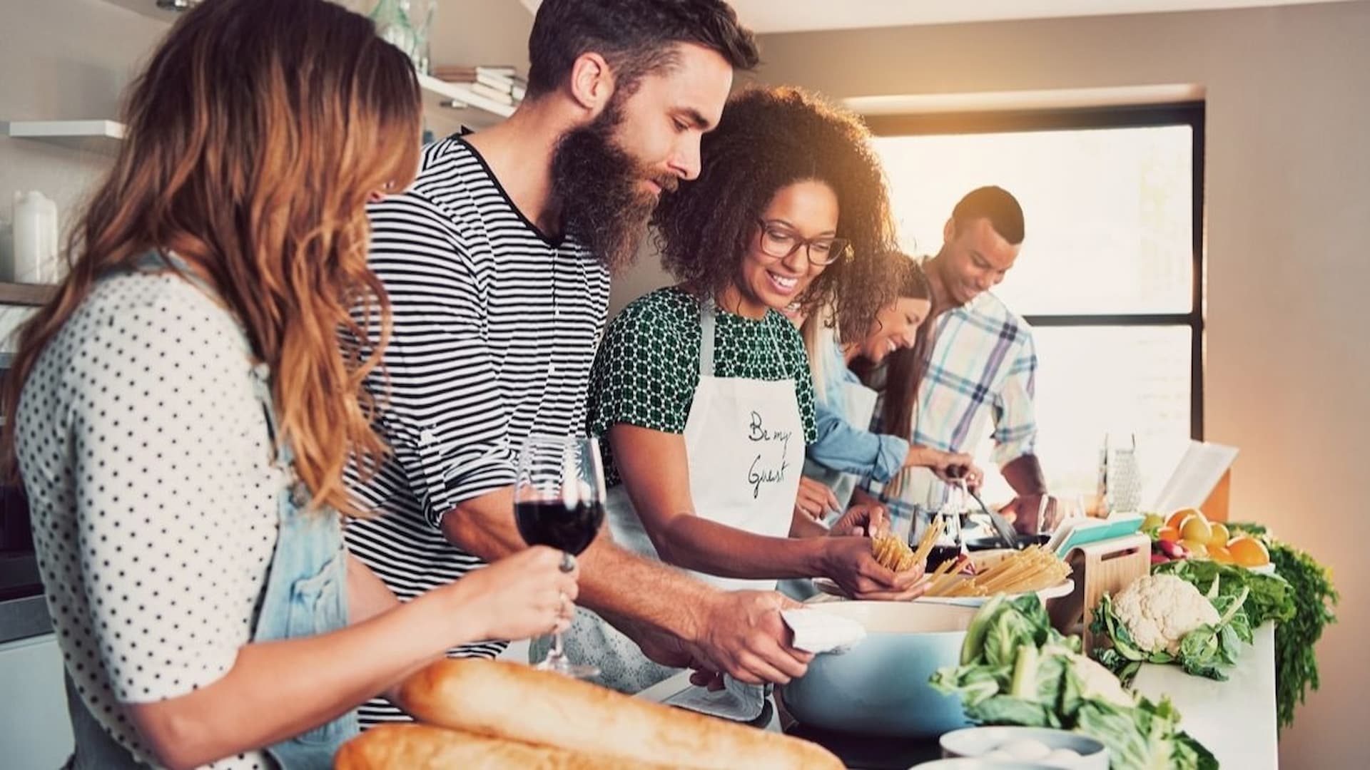 Group cooking together in a kitchen with ingredients.