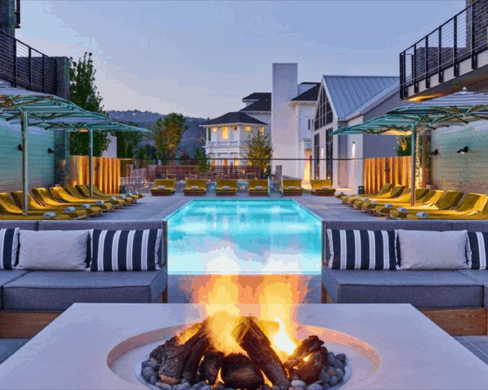 Cozy outdoor fire pit by modern poolside seating.