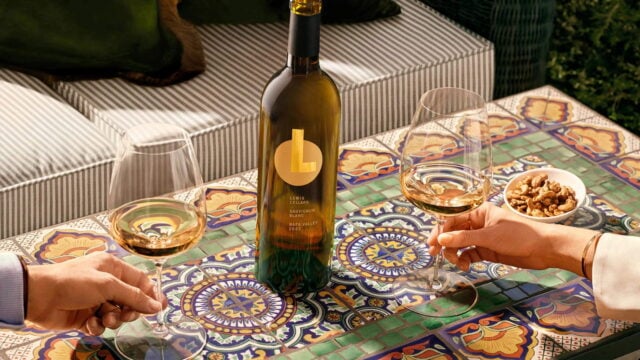 Wine bottle with two glasses on colorful table.