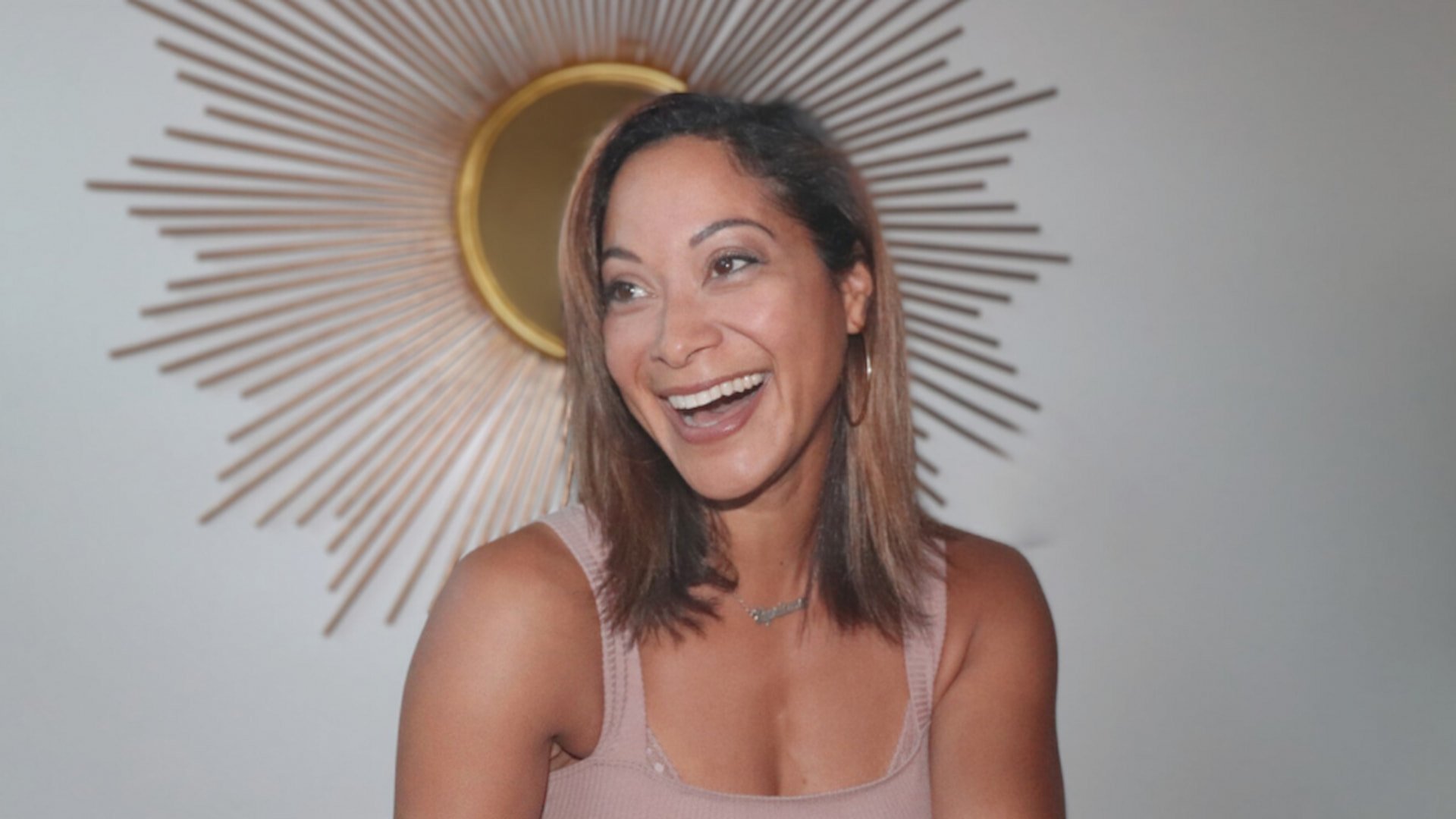 Smiling woman with decorative sunburst background.