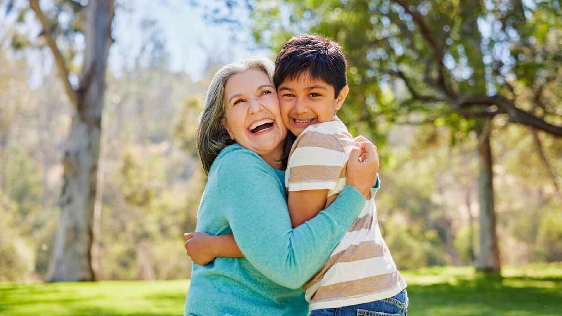 Happy grandmother hugging grandson outdoors