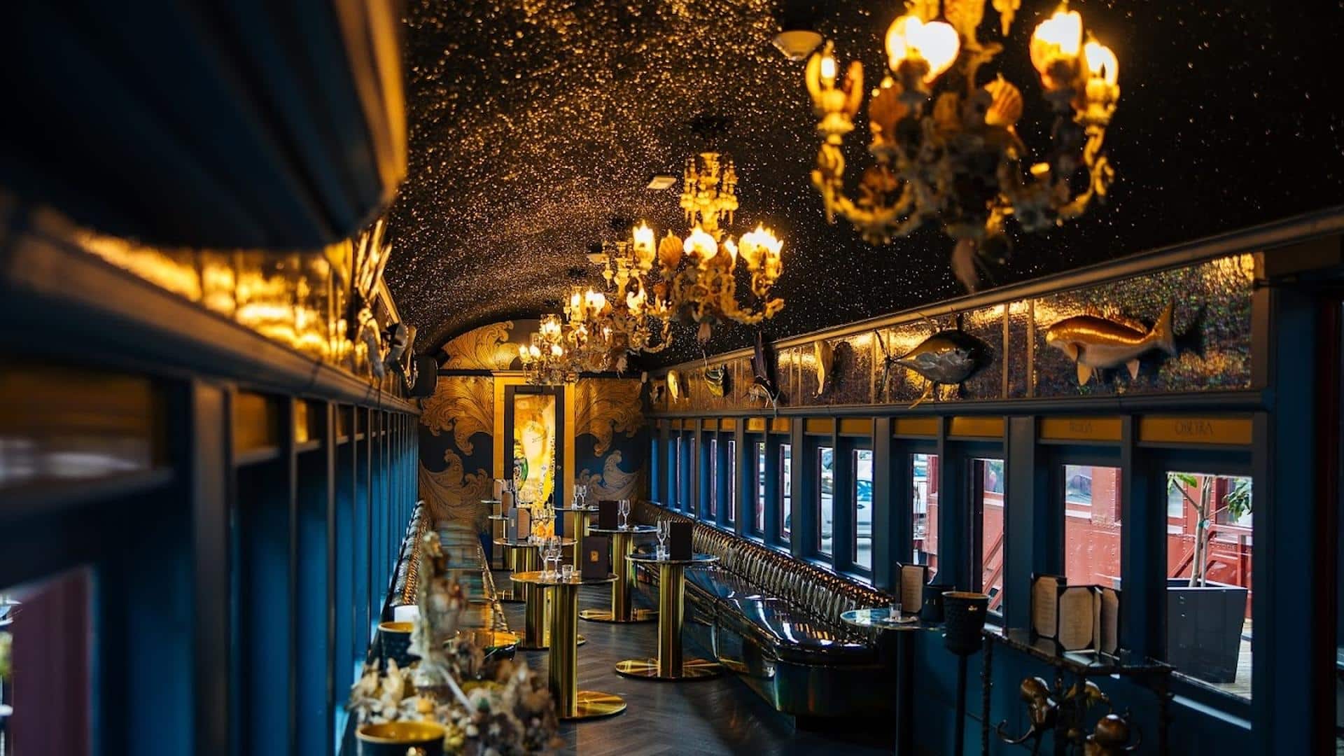 Luxurious train car restaurant with chandeliers and decor.
