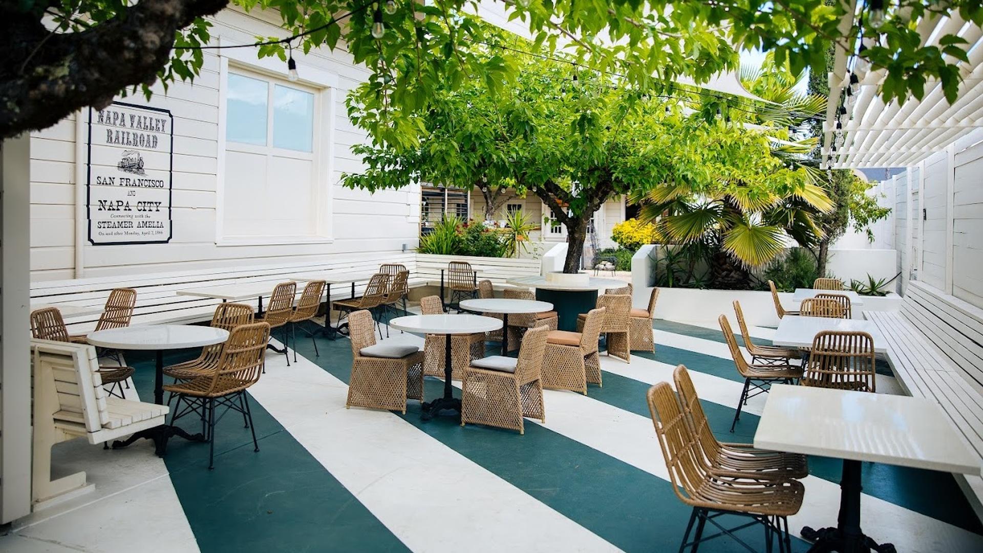 Outdoor patio with trees and wicker chairs.
