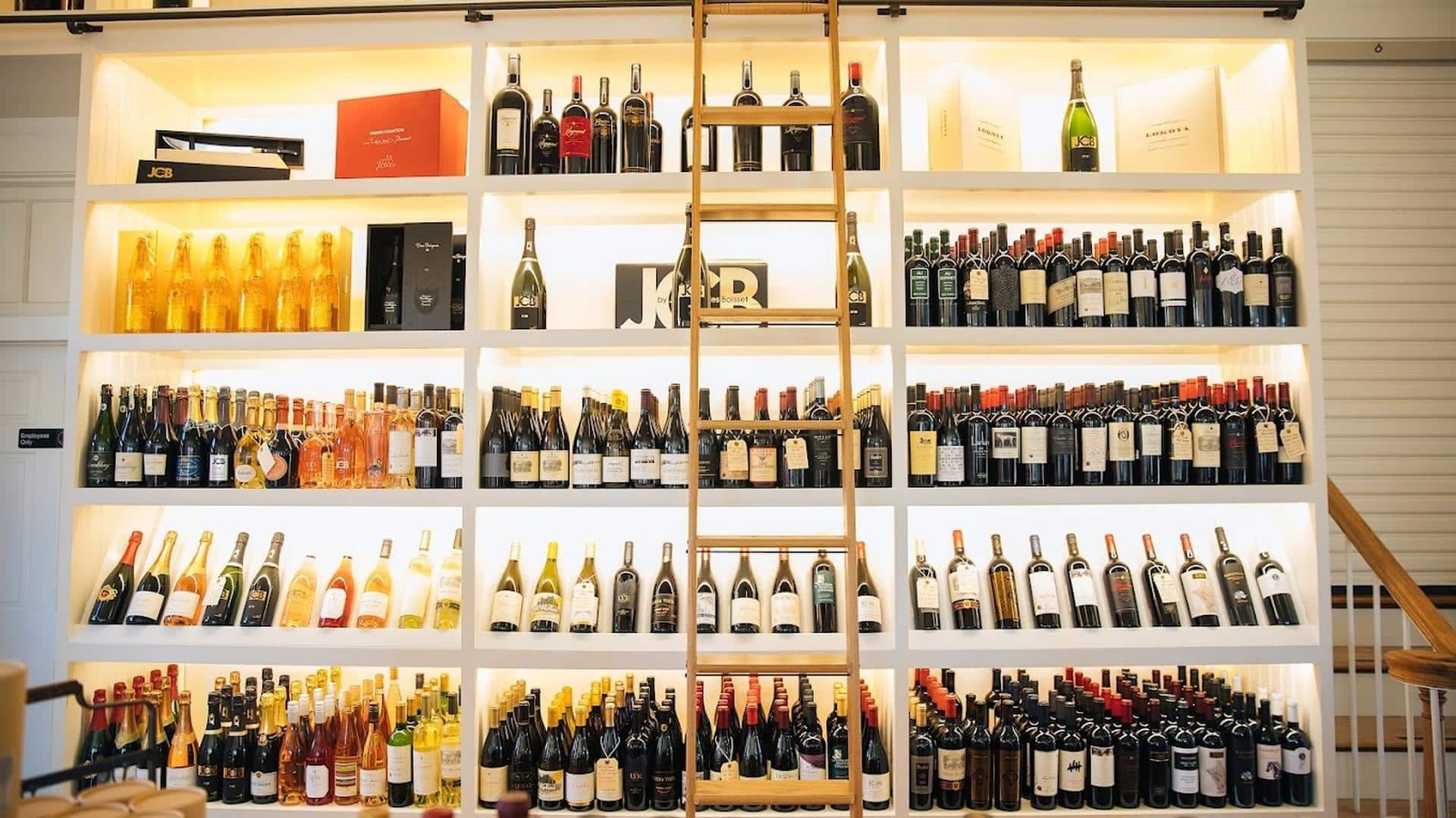 Wine bottles displayed on shelves with ladder.