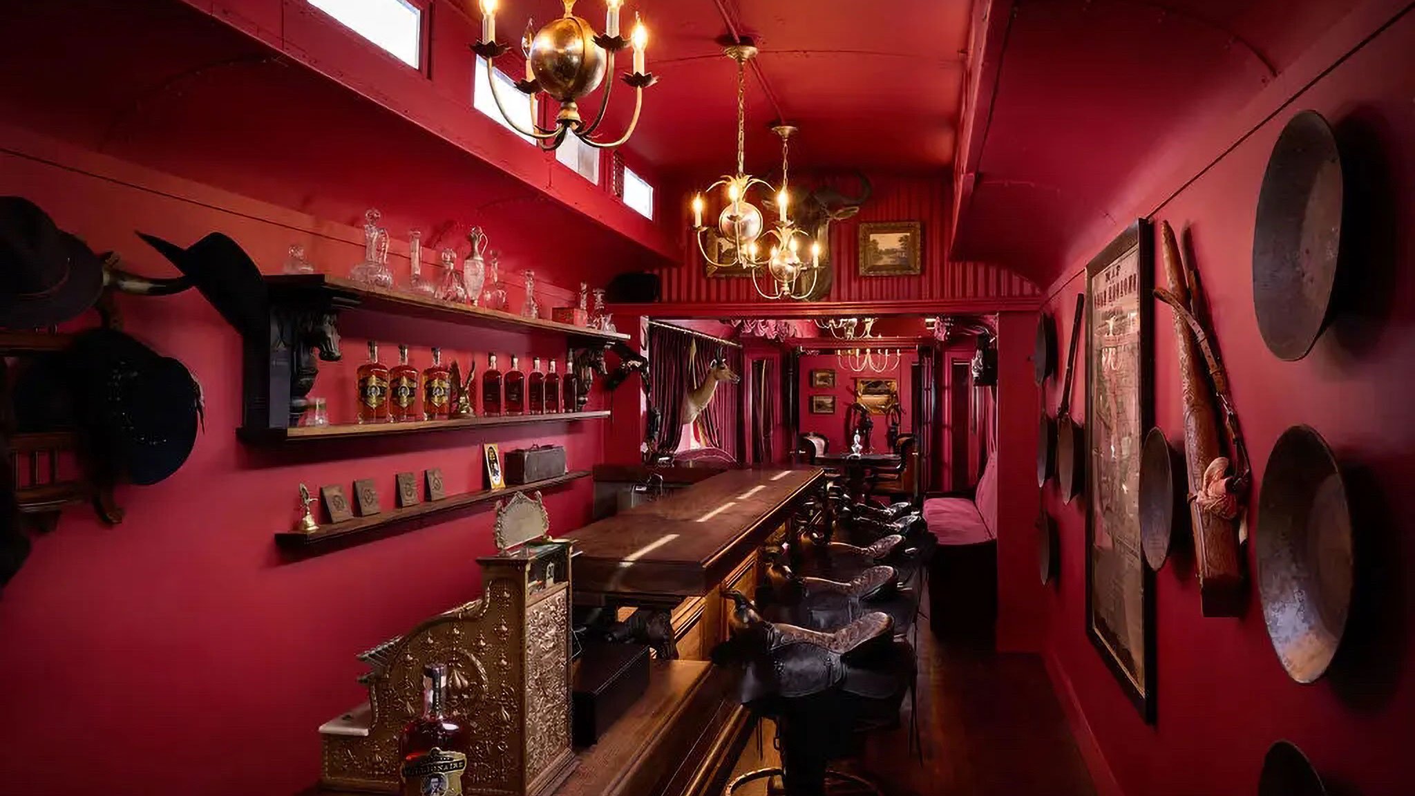 Red-themed vintage bar with chandeliers and decor.