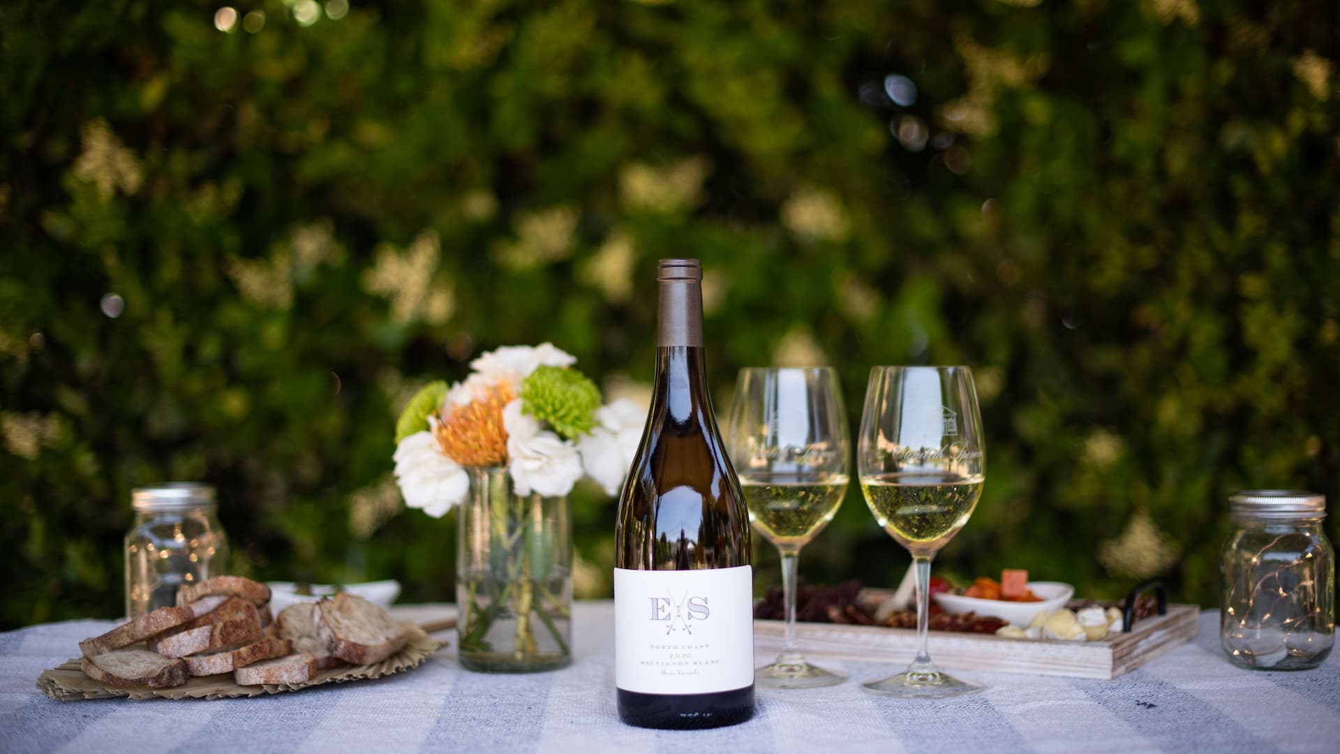 Outdoor wine and cheese setting with flowers.