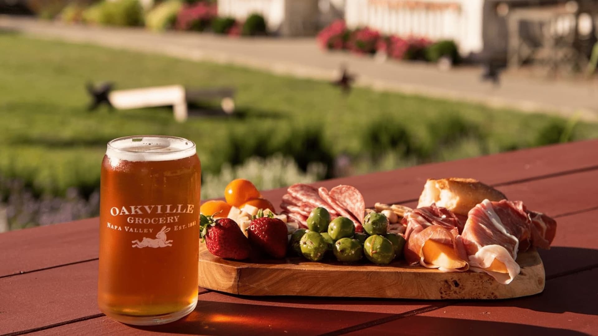 Beer and charcuterie board on outdoor table.