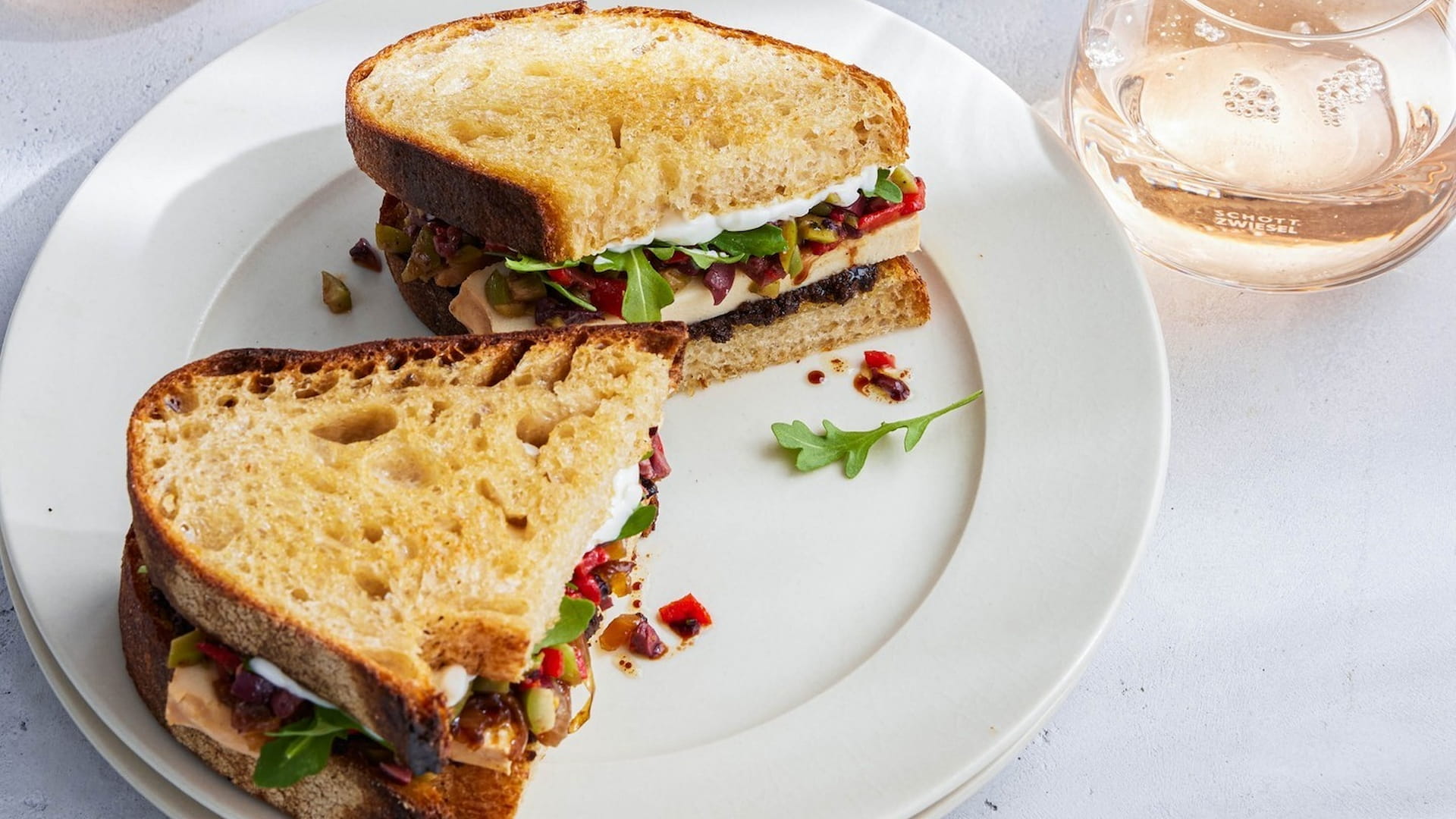 Gourmet sandwich with arugula and colorful toppings.