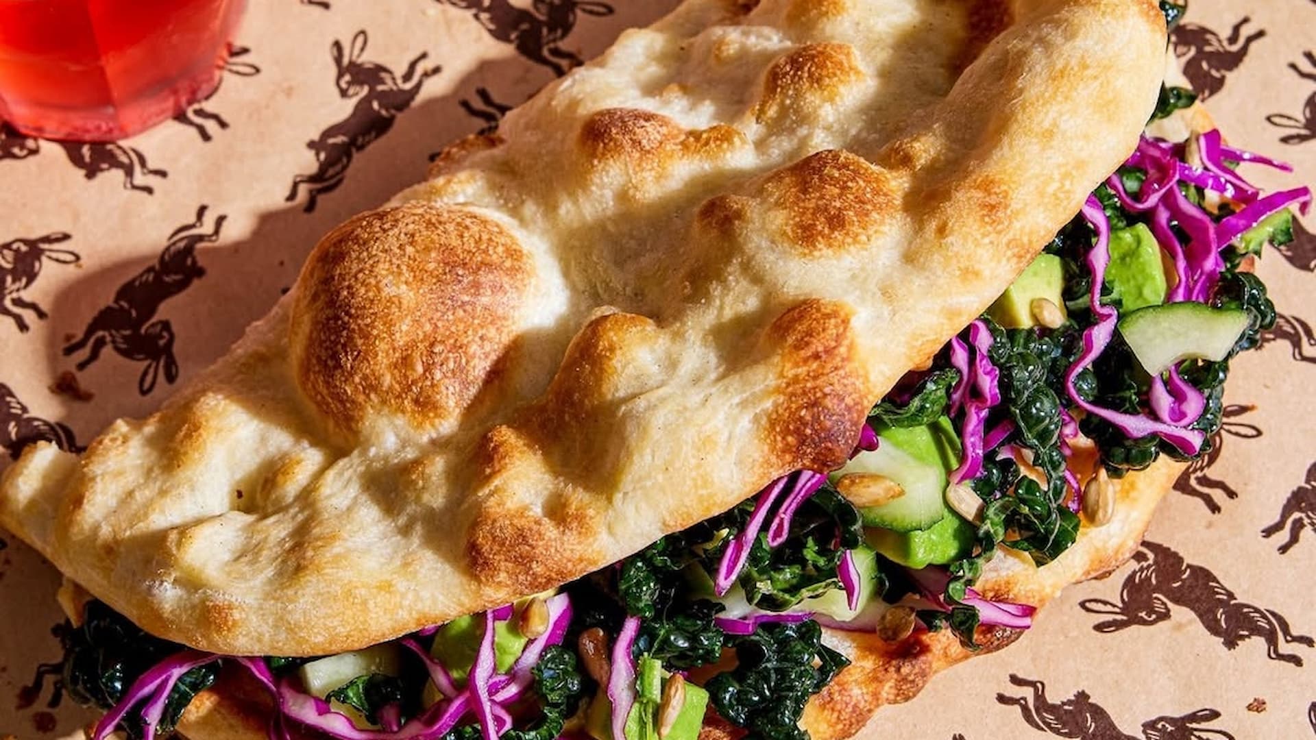 Vegetable sandwich with crispy bread and leafy greens.